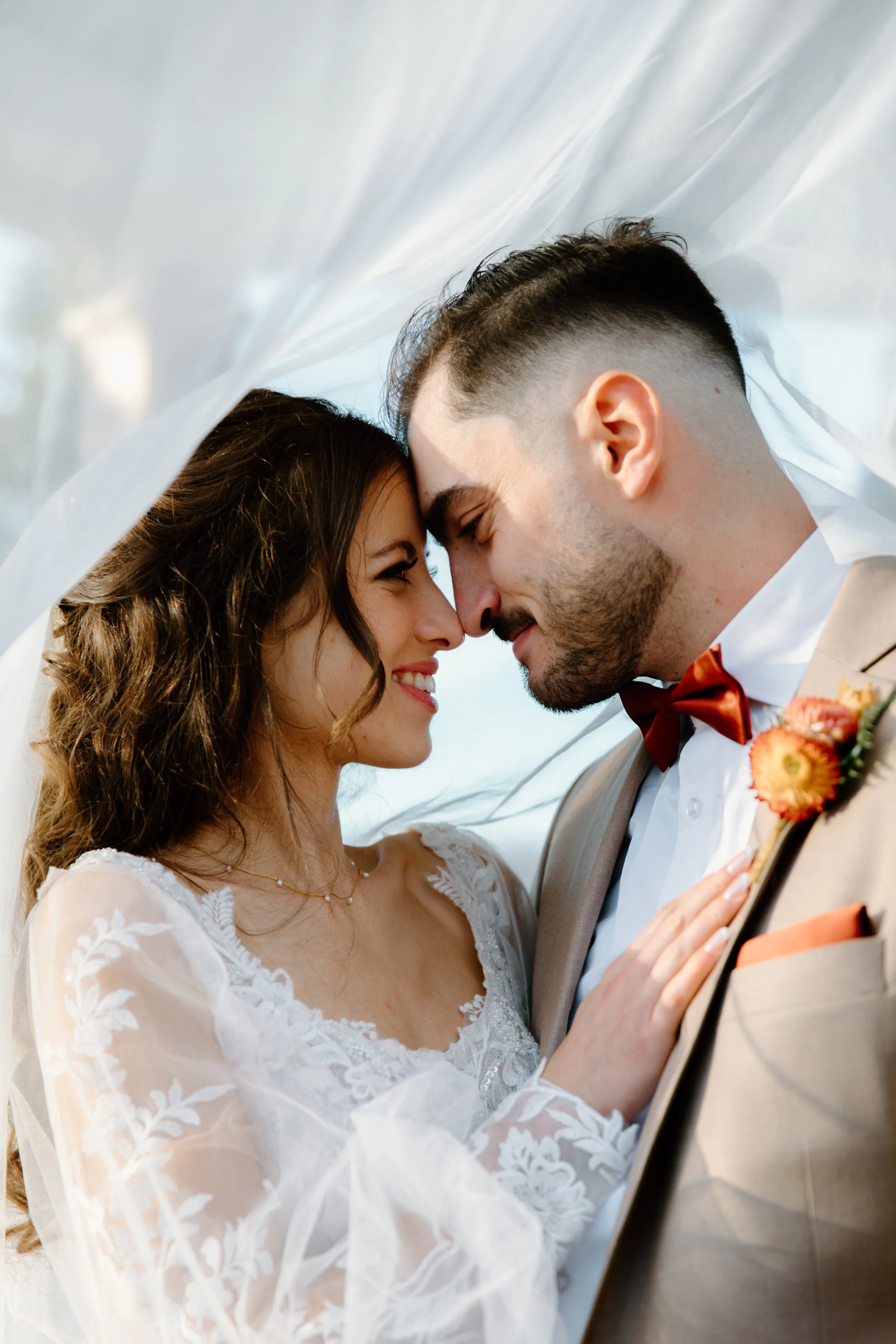 Trendy editorial inspired portrait of a bride and groom under the bridal veil at their Caledon wedding