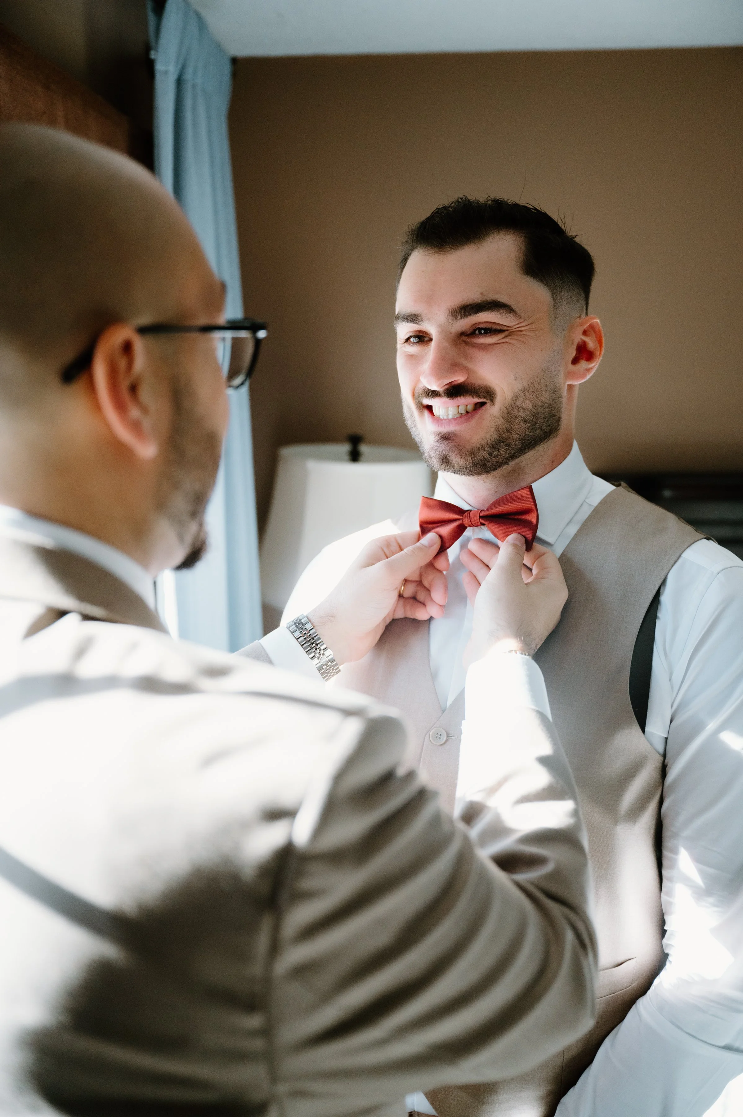 Candid photo of a groomsman helping the groom get ready on his Toronto wedding morning
