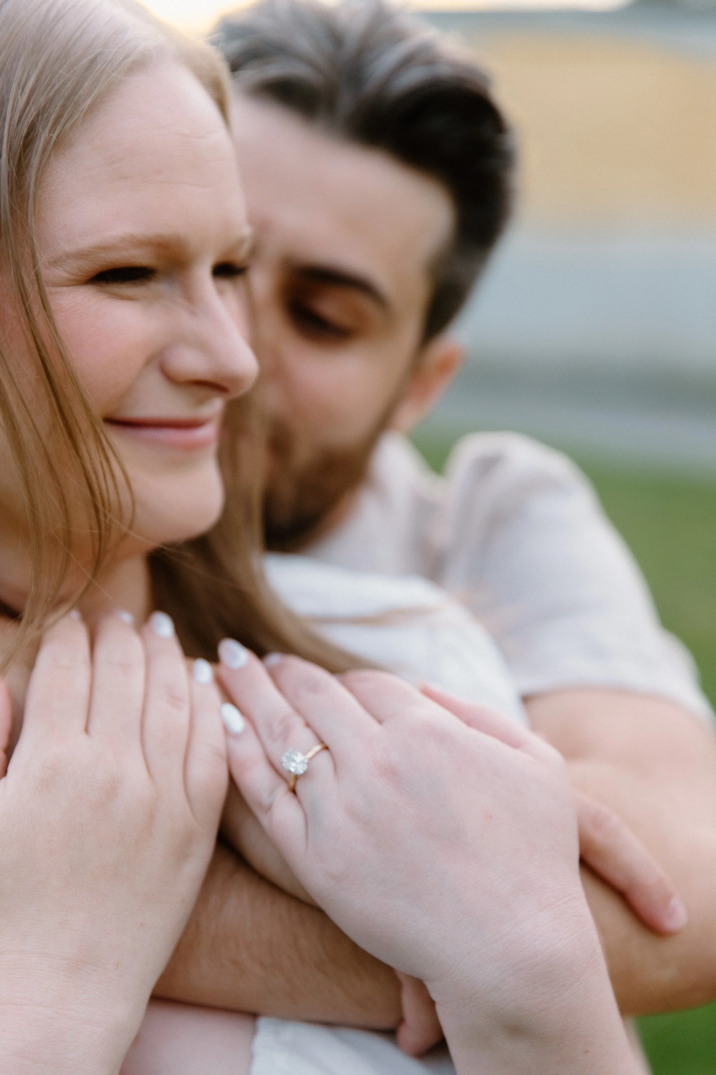 Detail photo focusing on an engagement ring as a couple embraces during their session at Dundurn Castle