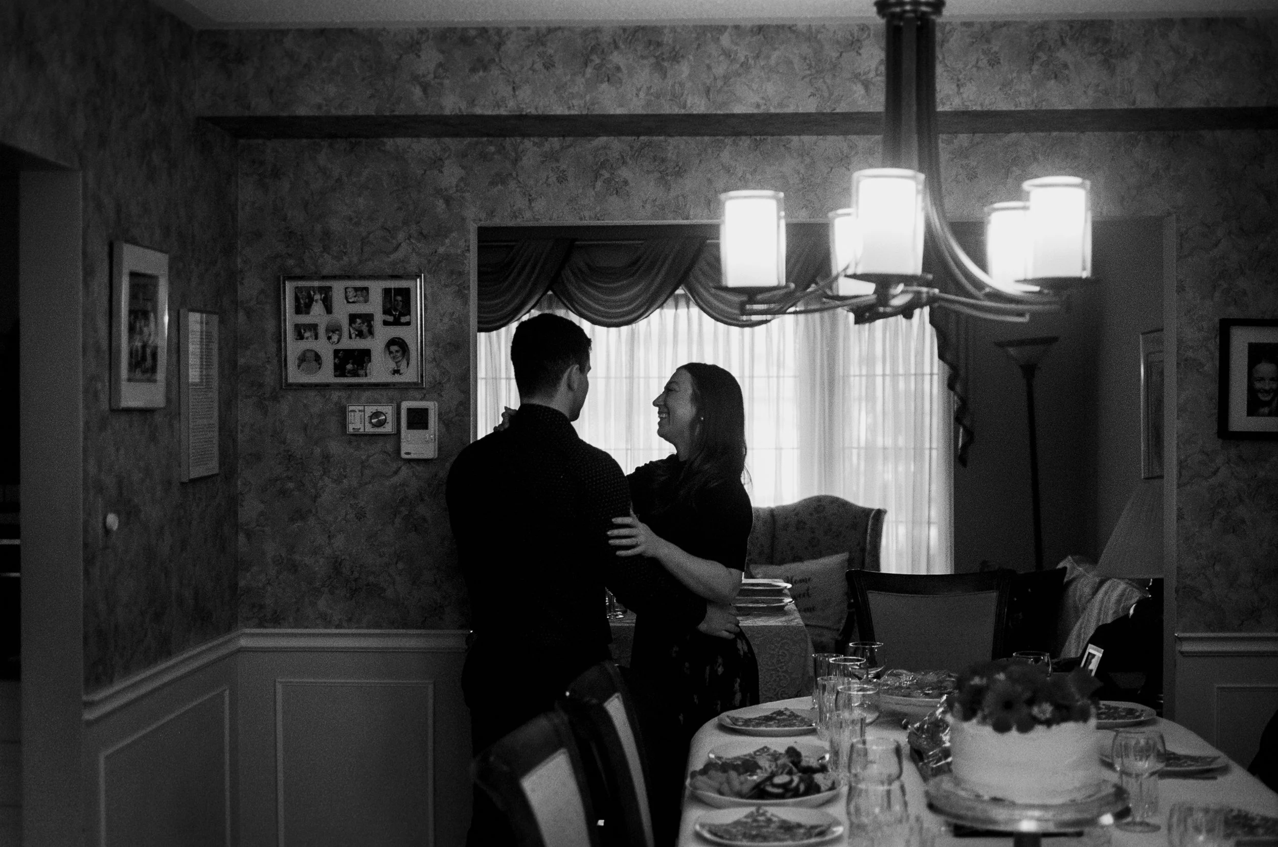 Black and white candid film photograph of guests gathered before an at-home wedding dinner in Vancouver