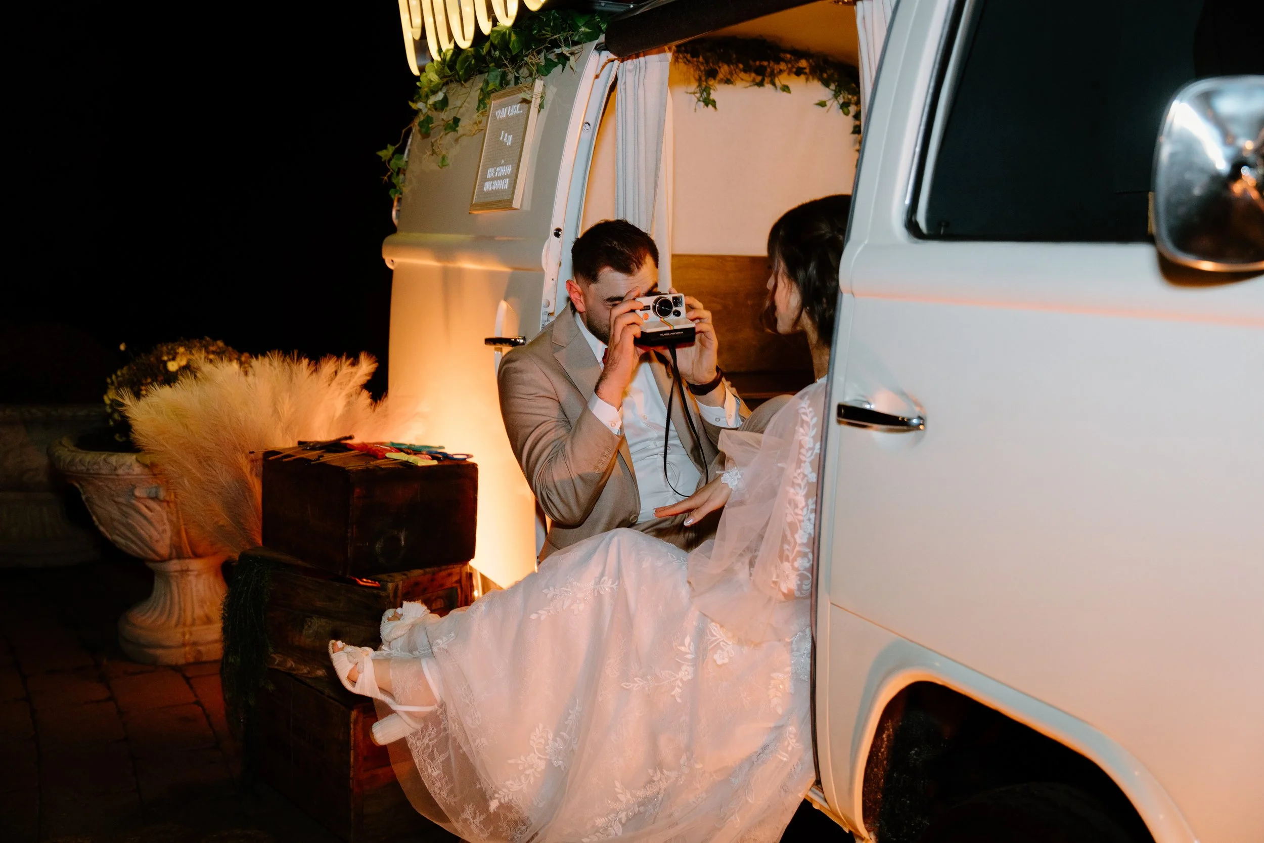 Candid photo of a groom taking a polaroid of his bride in a vintage VW truck at their Caledon wedding