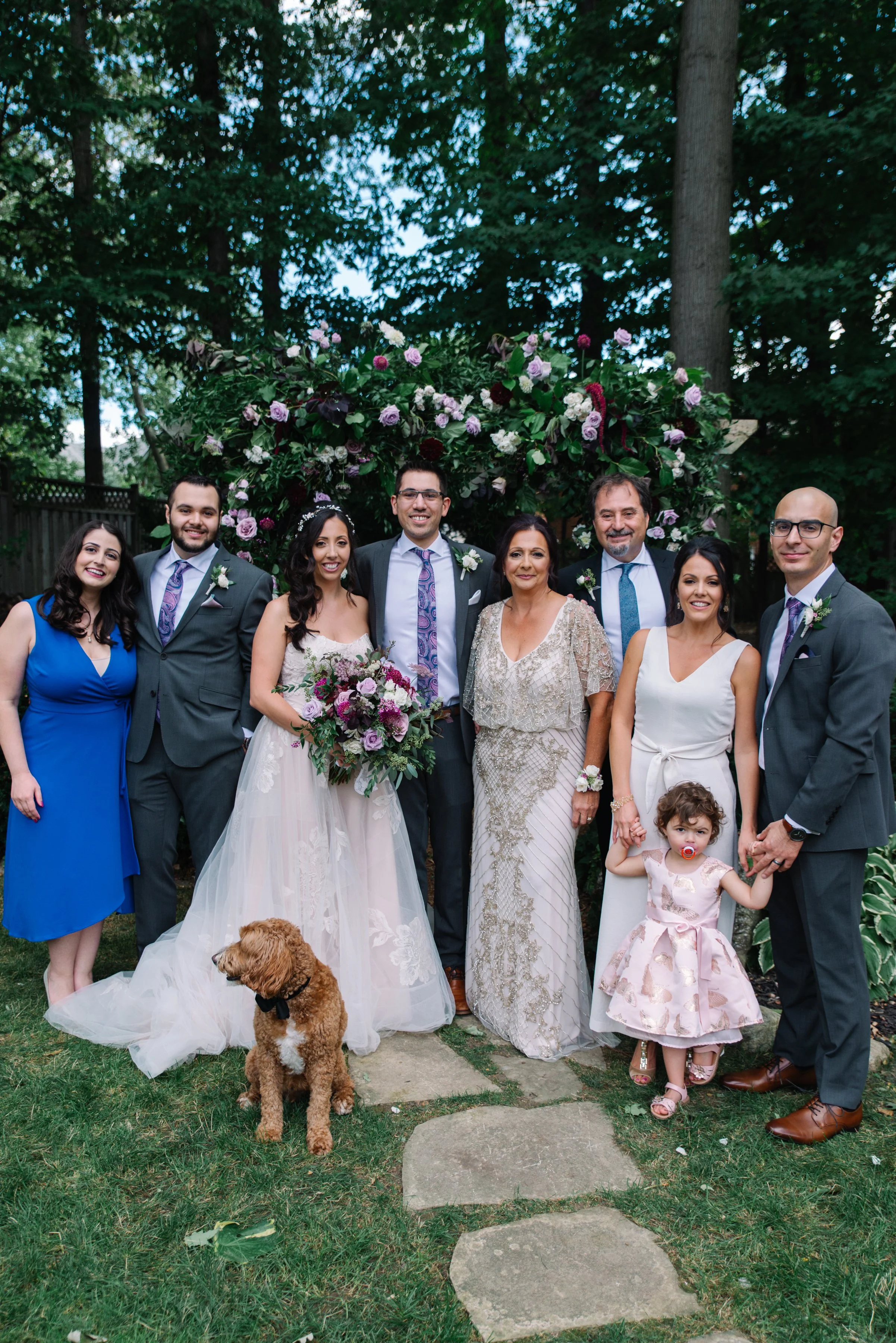Formal family portrait under a floral ceremony arch at an intimate backyard wedding
