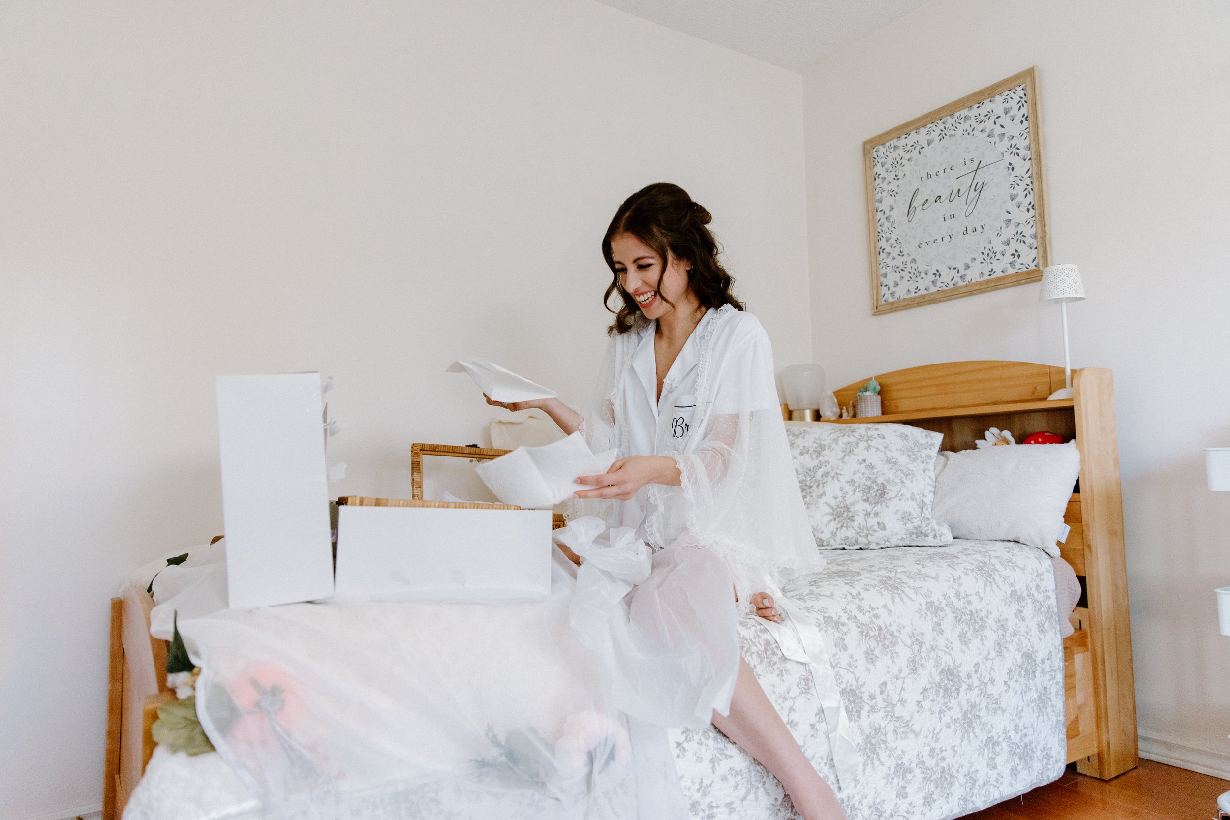 Candid photo of a bride smiling and laughing while reading a personal letter in her childhood room on her Toronto wedding morning
