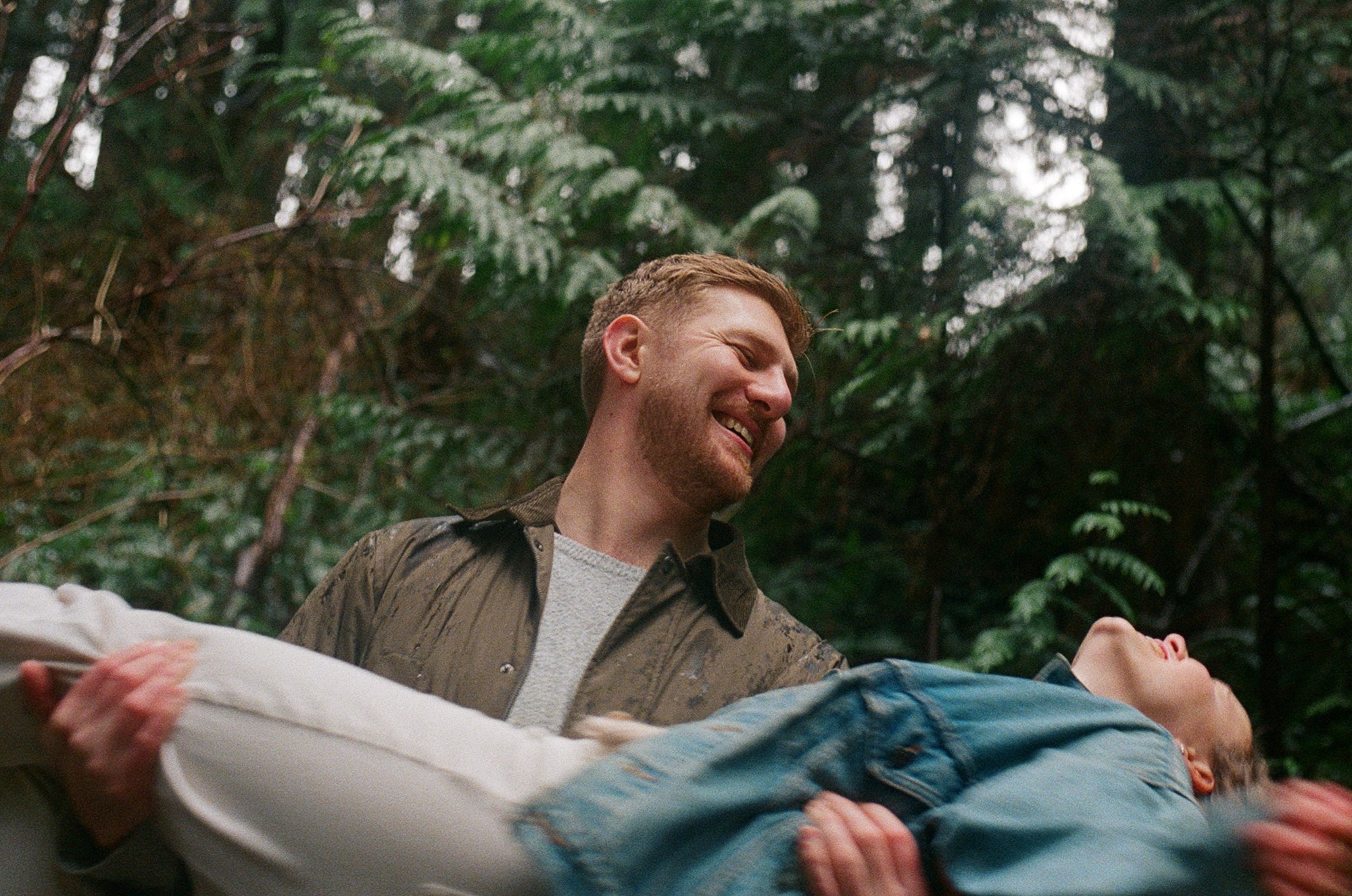 Candid film photograph with motion blur of a couple in an embrace as he is about to spin her around during their engagement session in Lynn Valley, Vancouver
