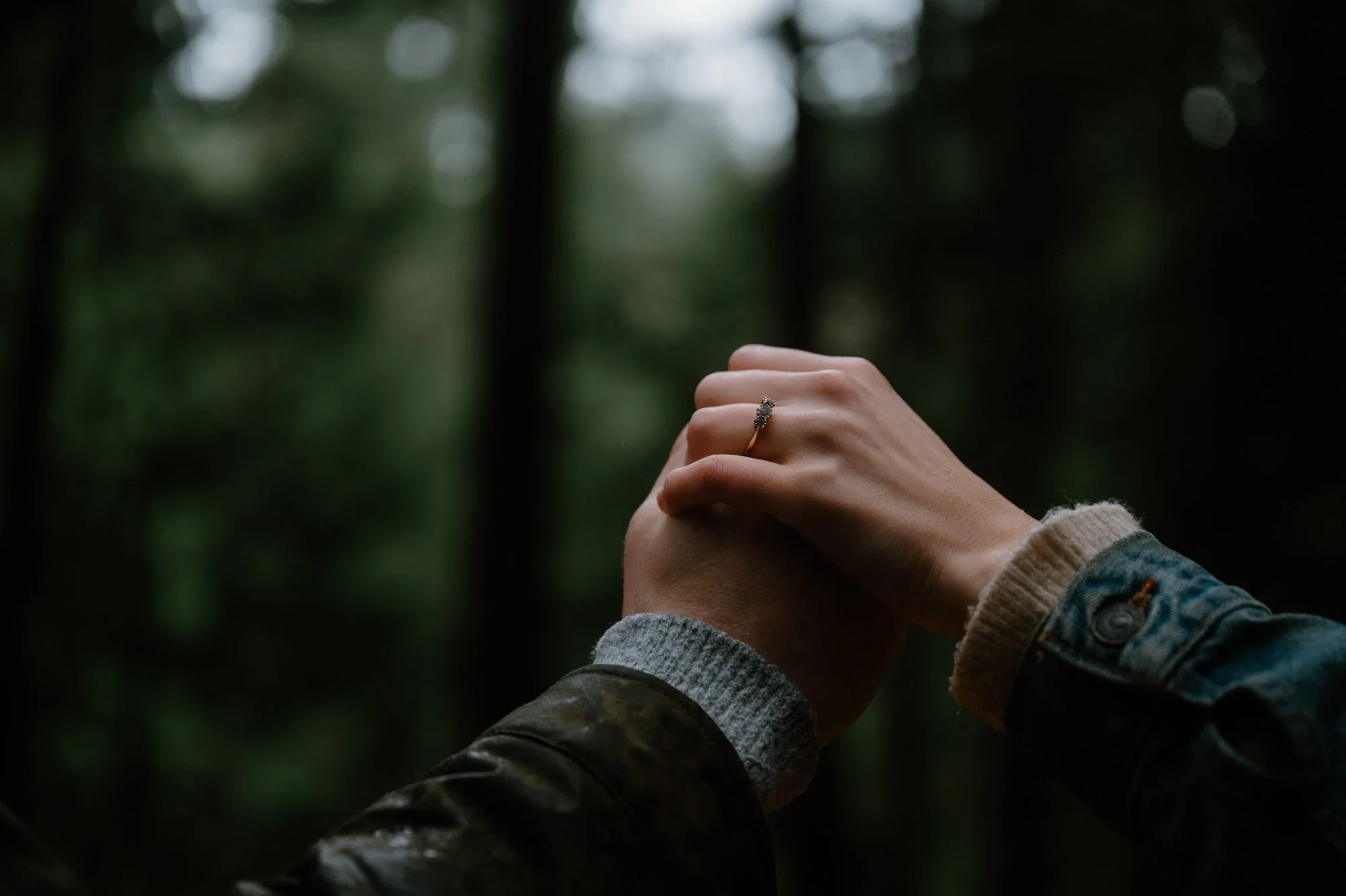 Detail photo of a couple's hands showing off an engagement ring during a rainy engagement session in Lynn Valley, North Vancouver