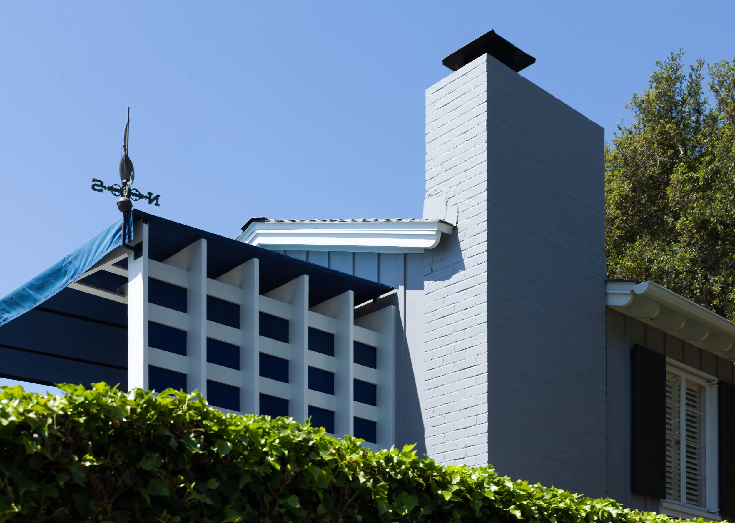 Exterior painting, Santa Barbara residence, blue brick chimney, white trellis, dark blue canvass awning