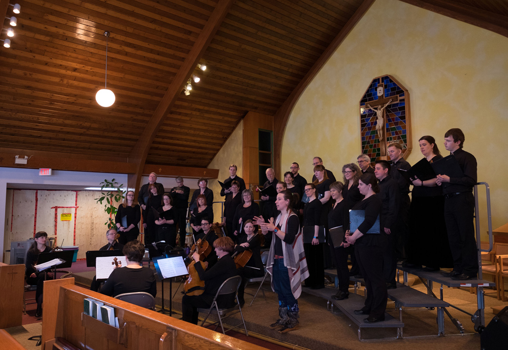 Carmen Braden introduces "The Ice Seasons" before its Yellowknife premier, explaining how each of the six movements represent the six different states of water and ice, as the six-member string ensemble look on.
