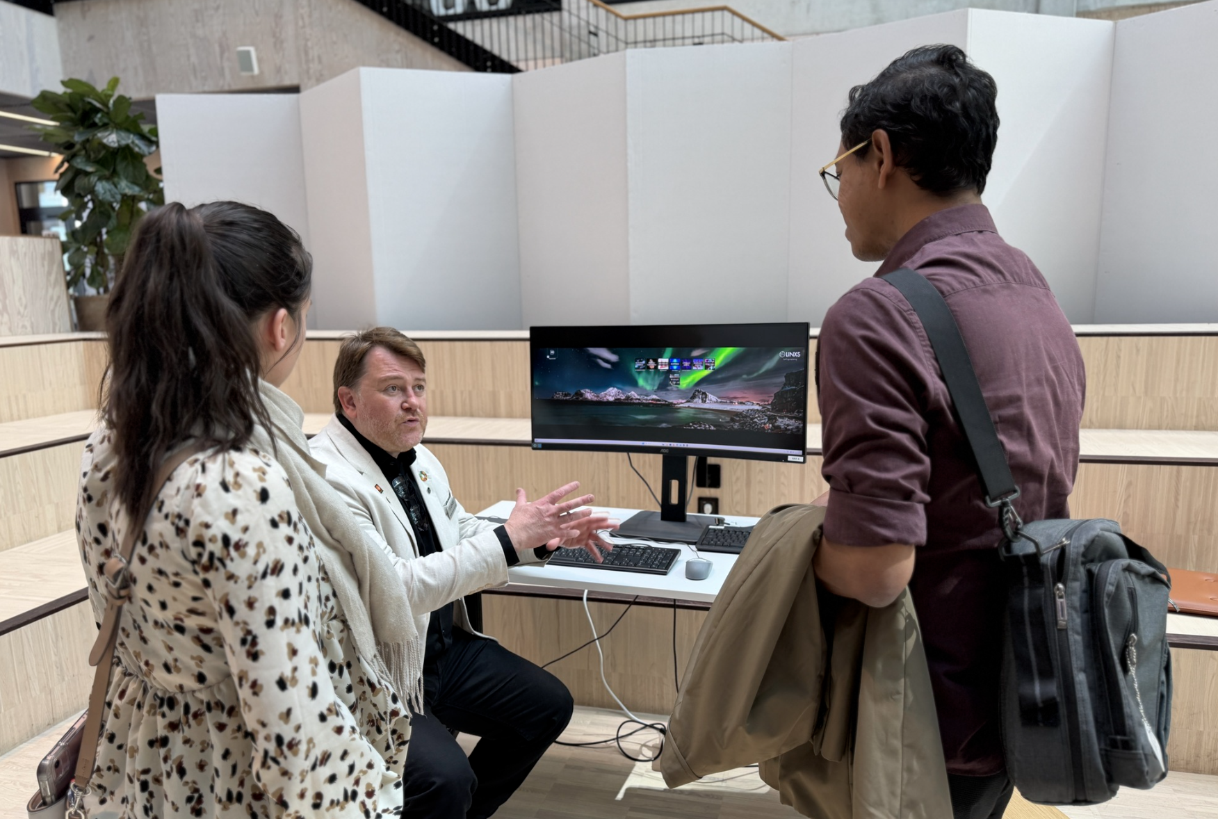 Three people in front of a computer at LINXS. Photo.