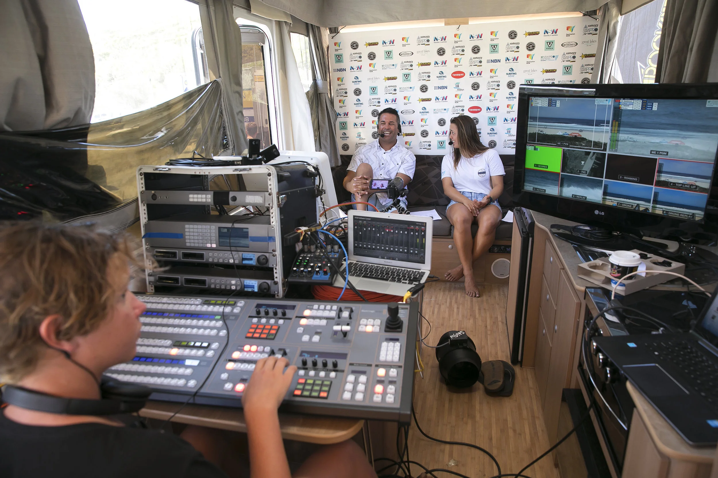 John Shimooka (centre) commentating in a trailer studio at Boomerang beach.