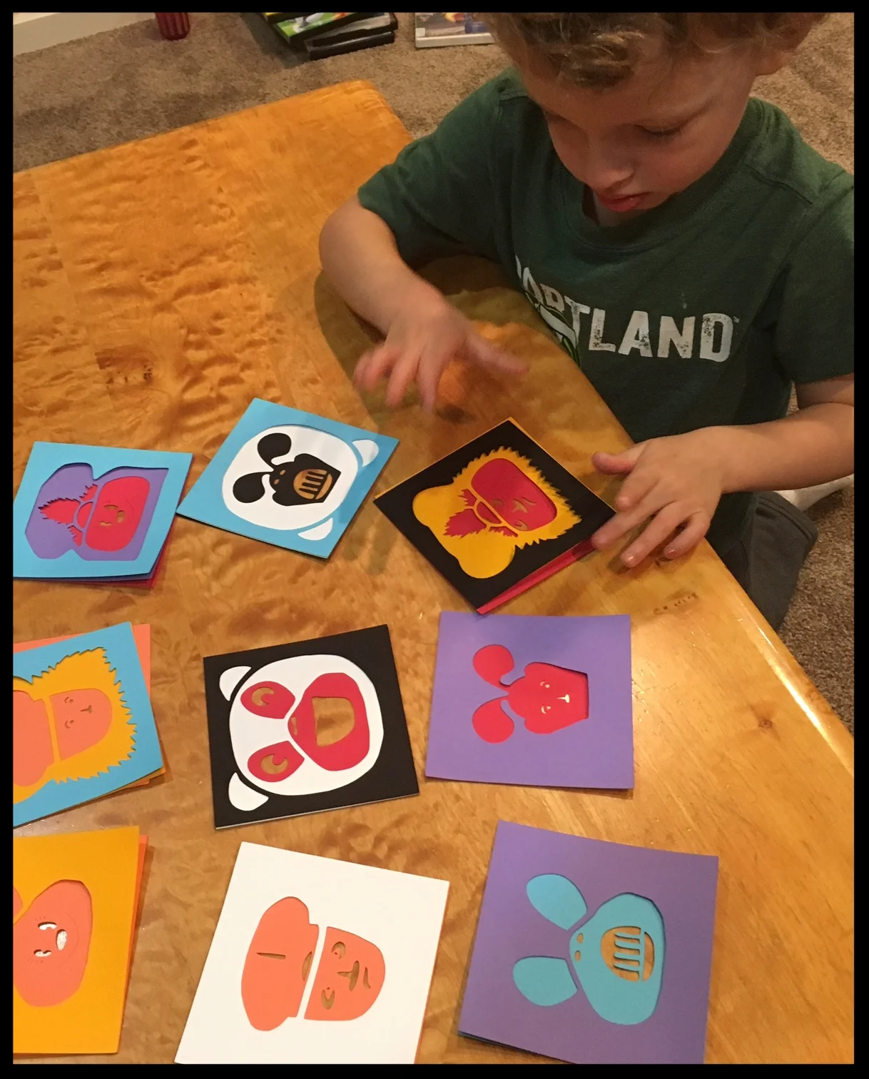 My three year old son interacts with layered paper cuts by mixing and matching designs and colored faces.