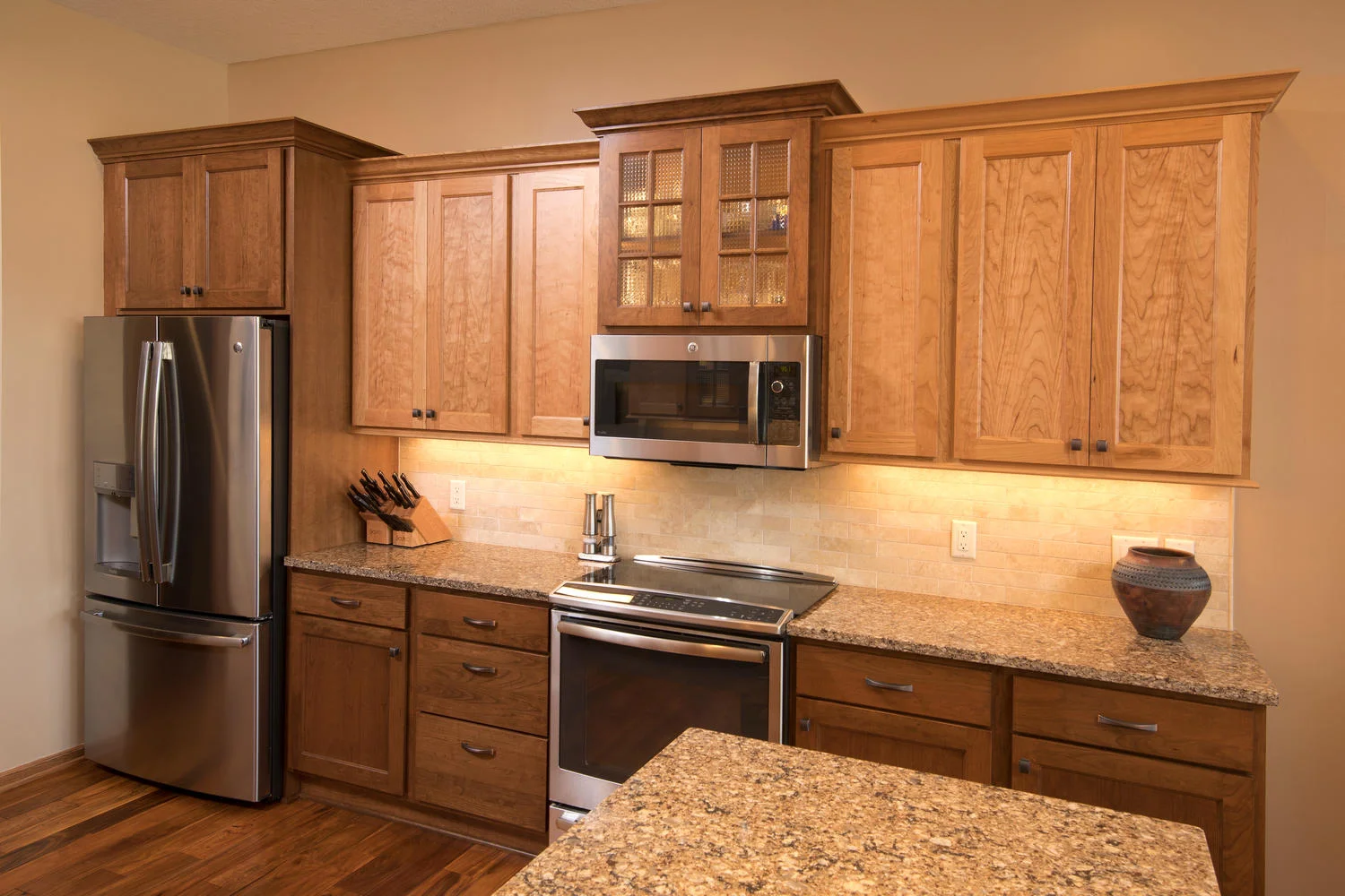 Tan kitchen with wood stained cabinets, countertops and tile backsplash