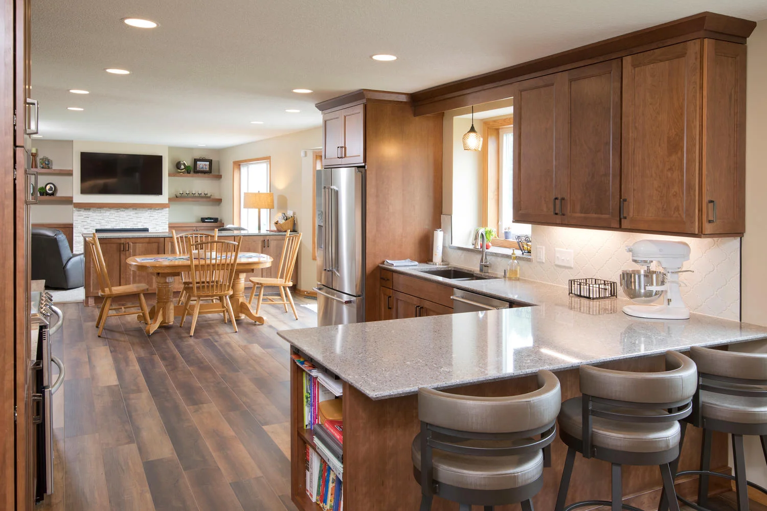 Kitchen remodel with wood grain floor, peninsula with quartz countertops, and stained cabinets