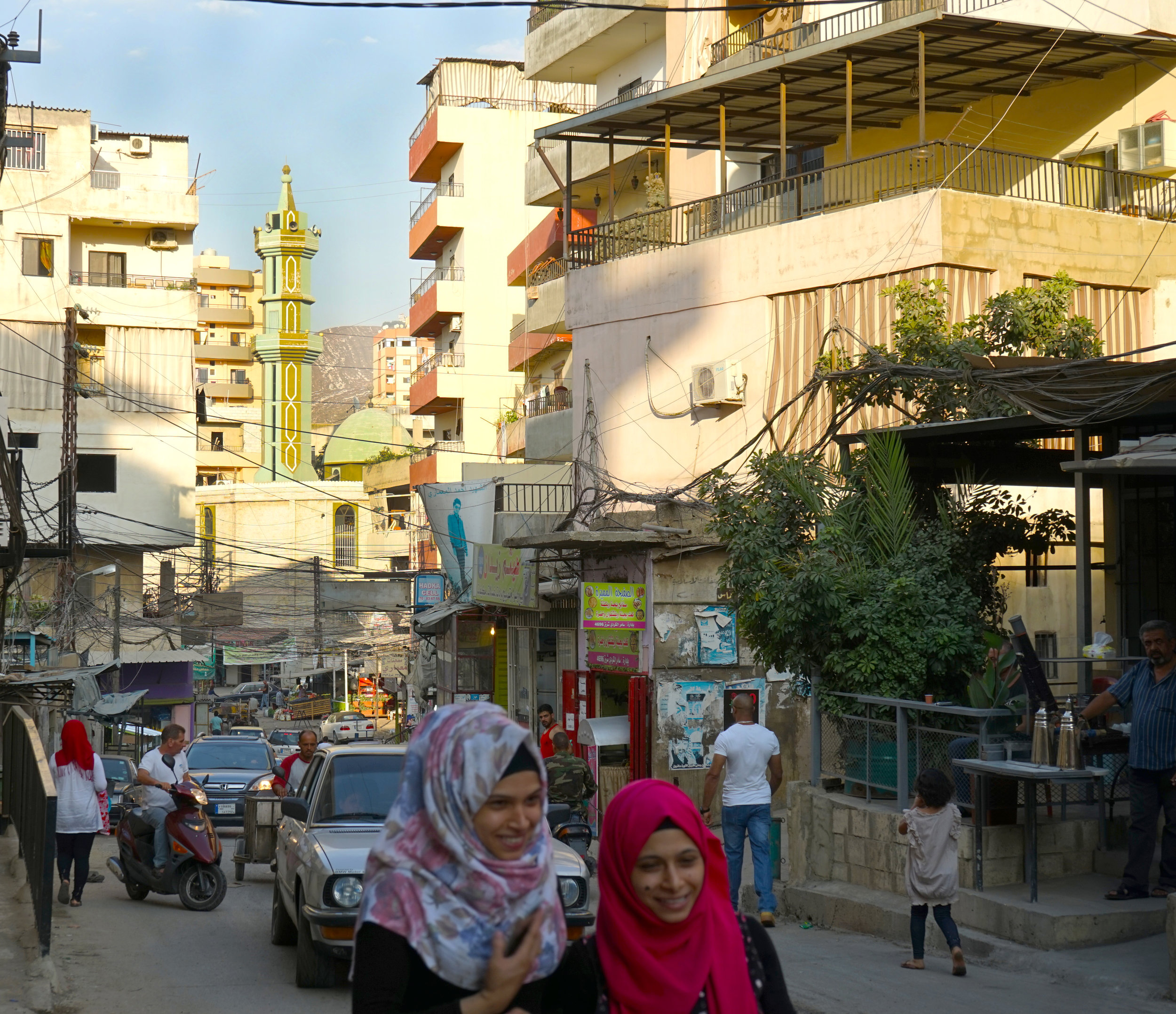  Two girls walk down the street of Camp Beddawi on August 20, 2016, with the Camp's mosque looming in the background. 