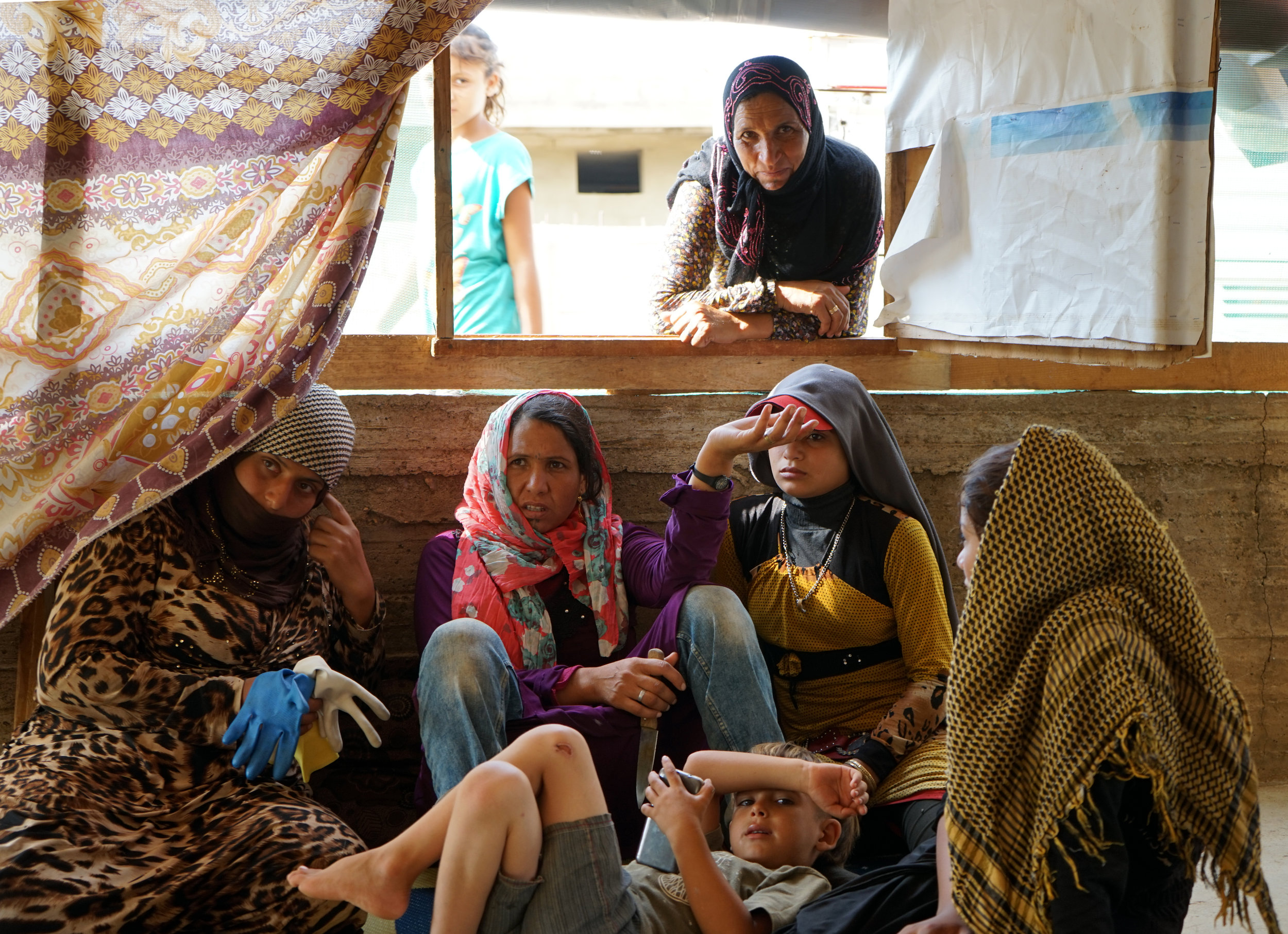  A group of women sit together in a tent in a UNHCR Syrian refugee in 'Akkar, Lebanon on August 23, 2016. 