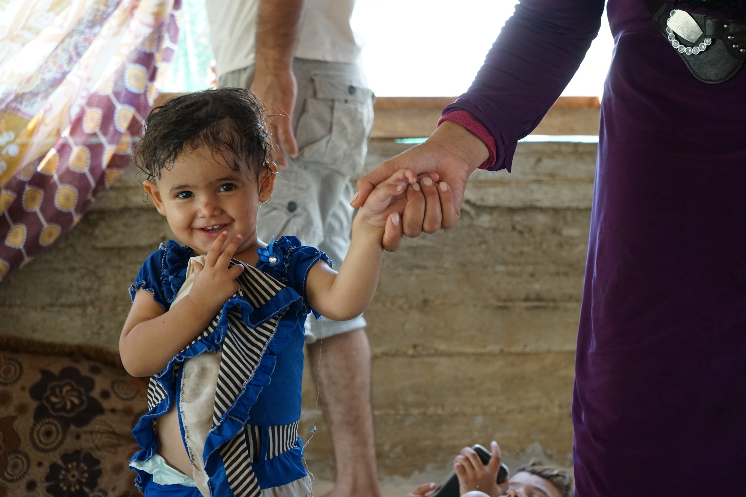  A little girl giggles in a tent in a UNHCR refugee camp in 'Akkar, Lebanon on August 23, 2016. 