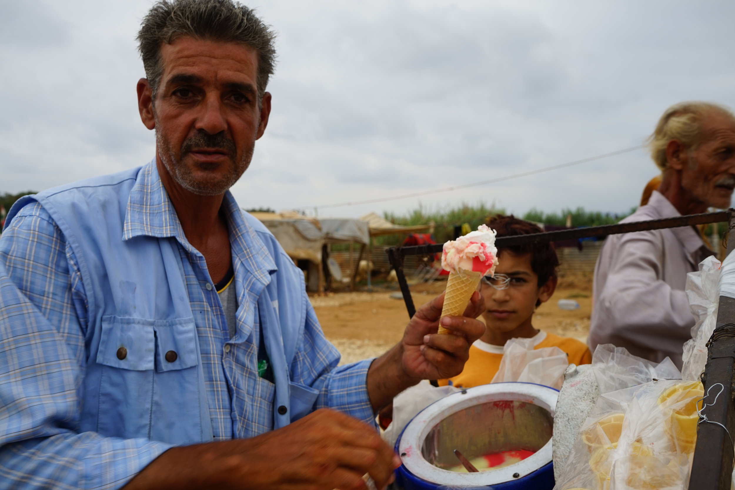  A UNHCR worker gives out free ice cream to residents of UNHCR Syrian refugee camp 054 in 'Akkar on August 24, 2016. 