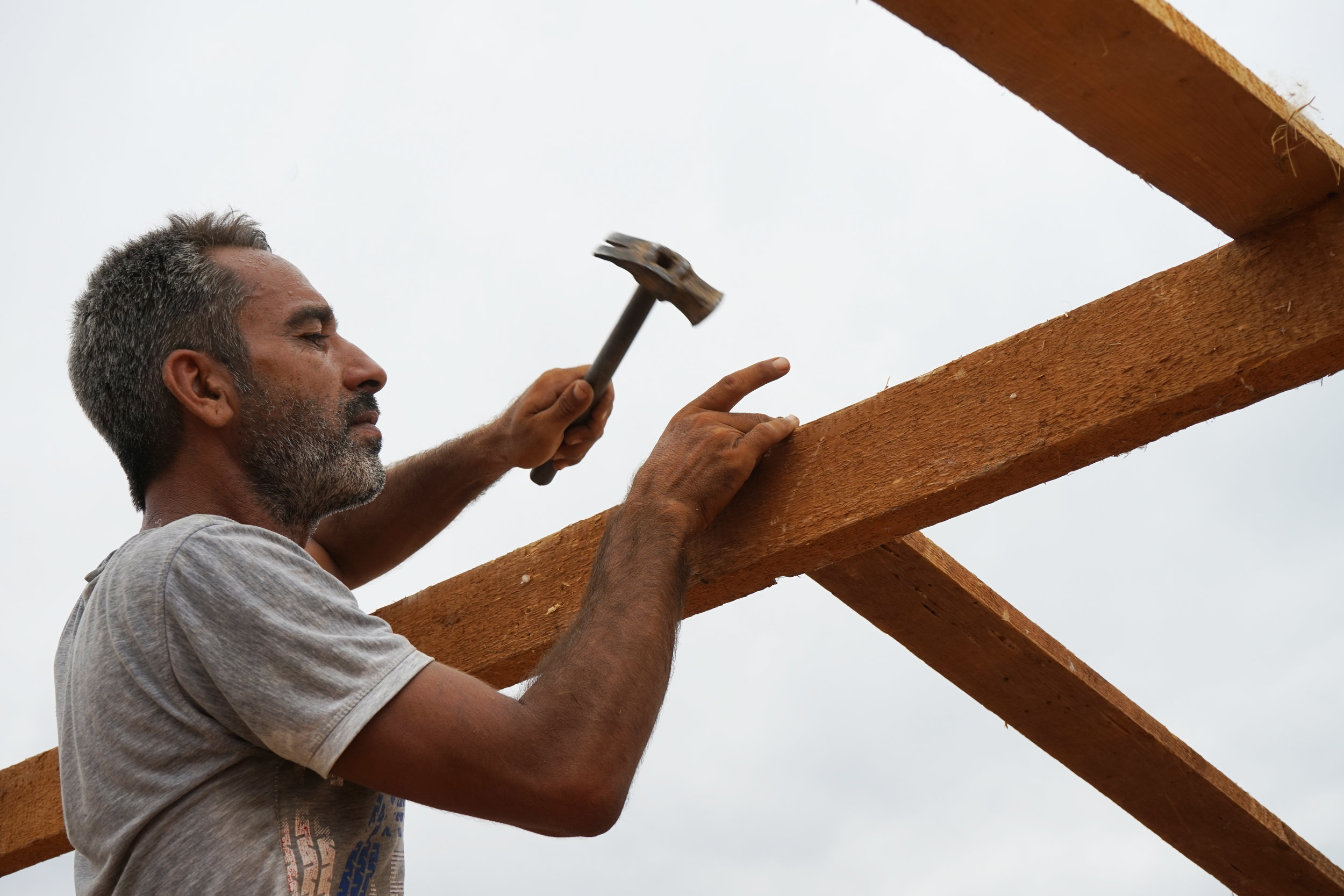  A man works on building the structure for a new tent in UNHCR Syrian refugee camp 054 in 'Akkar on August 24, 2016. 