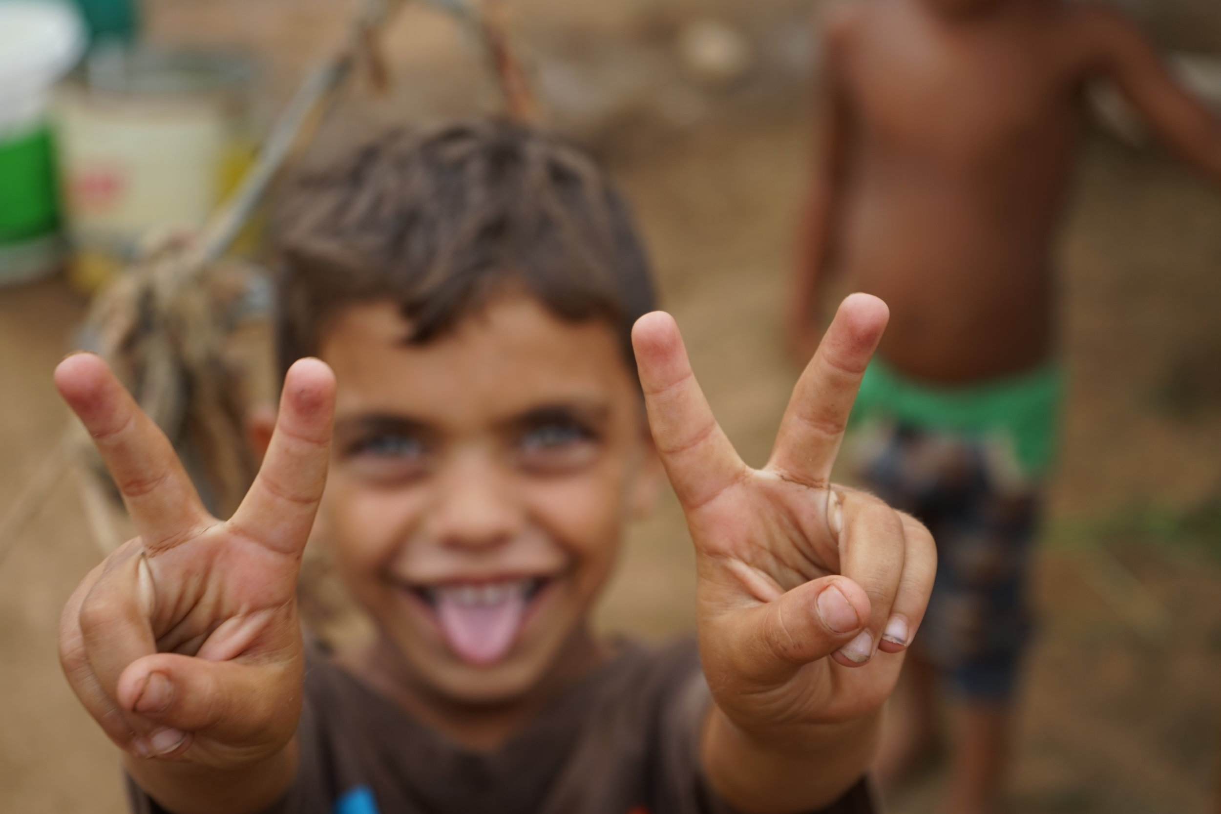  A young boy holds up peace signs in UNHCR Syrian refugee camp 054 in 'Akkar on August 24, 2016. 