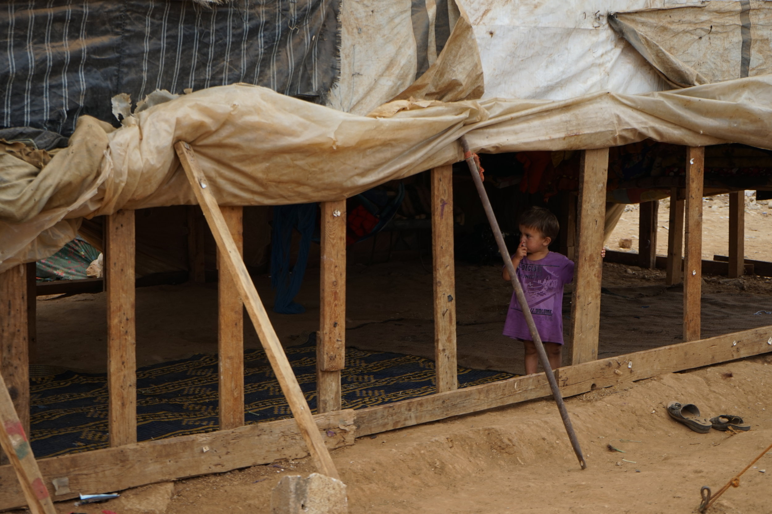  A little girl stands in a tent in UNHCR Syrian refugee camp 054 in 'Akkar on August 24, 2016. 