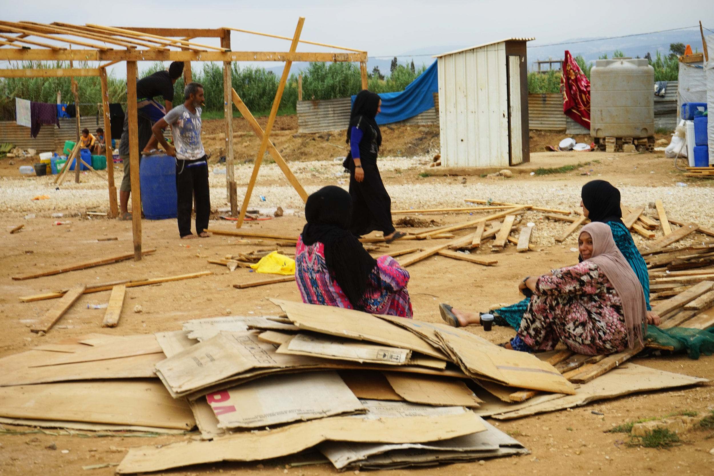  Syrian refugees sit around the construction of a tent structure in UNHCR Syrian refugee camp 054 in 'Akkar on August 24, 2016. 