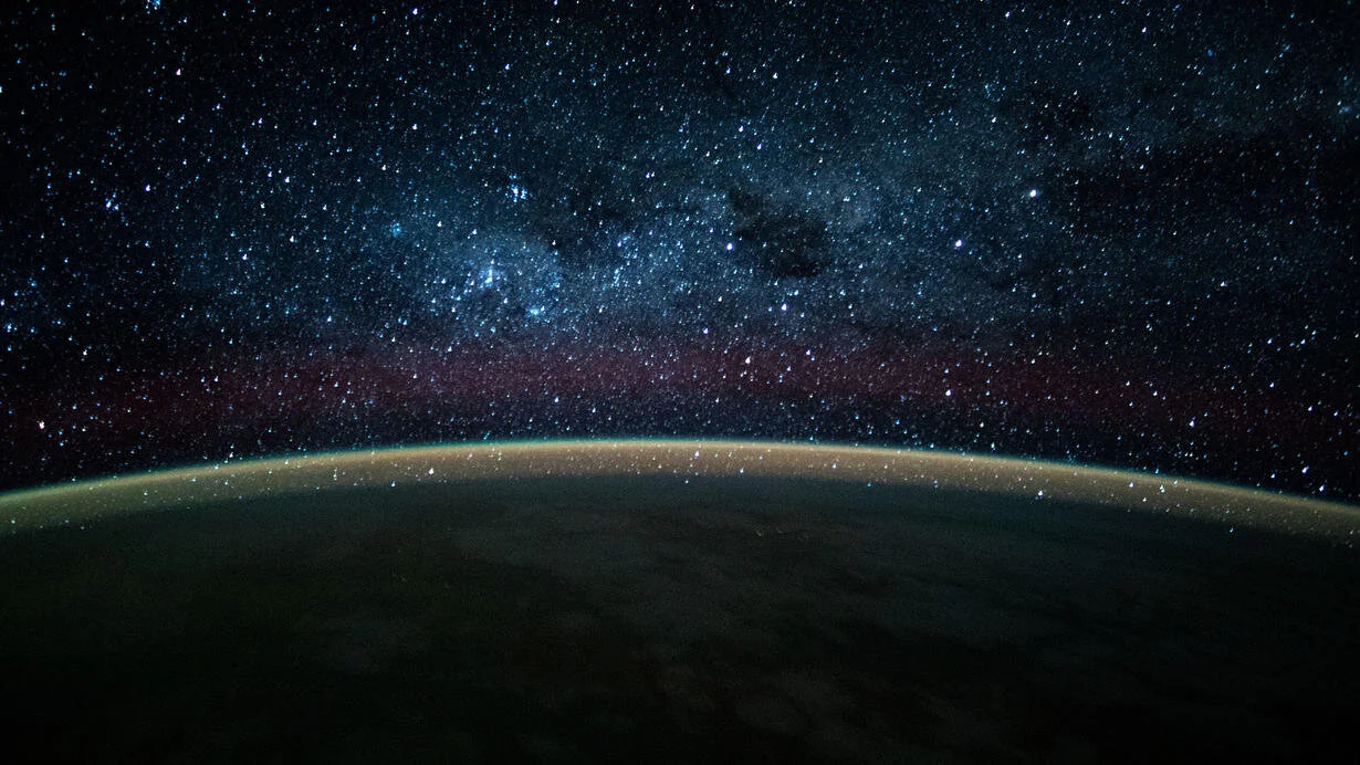 This long-exposure photograph taken from the International Space Station reveals a colorful atmospheric glow crowning Earth's horizon, back-dropped by the dazzling Milky Way. Courtesy of NASA