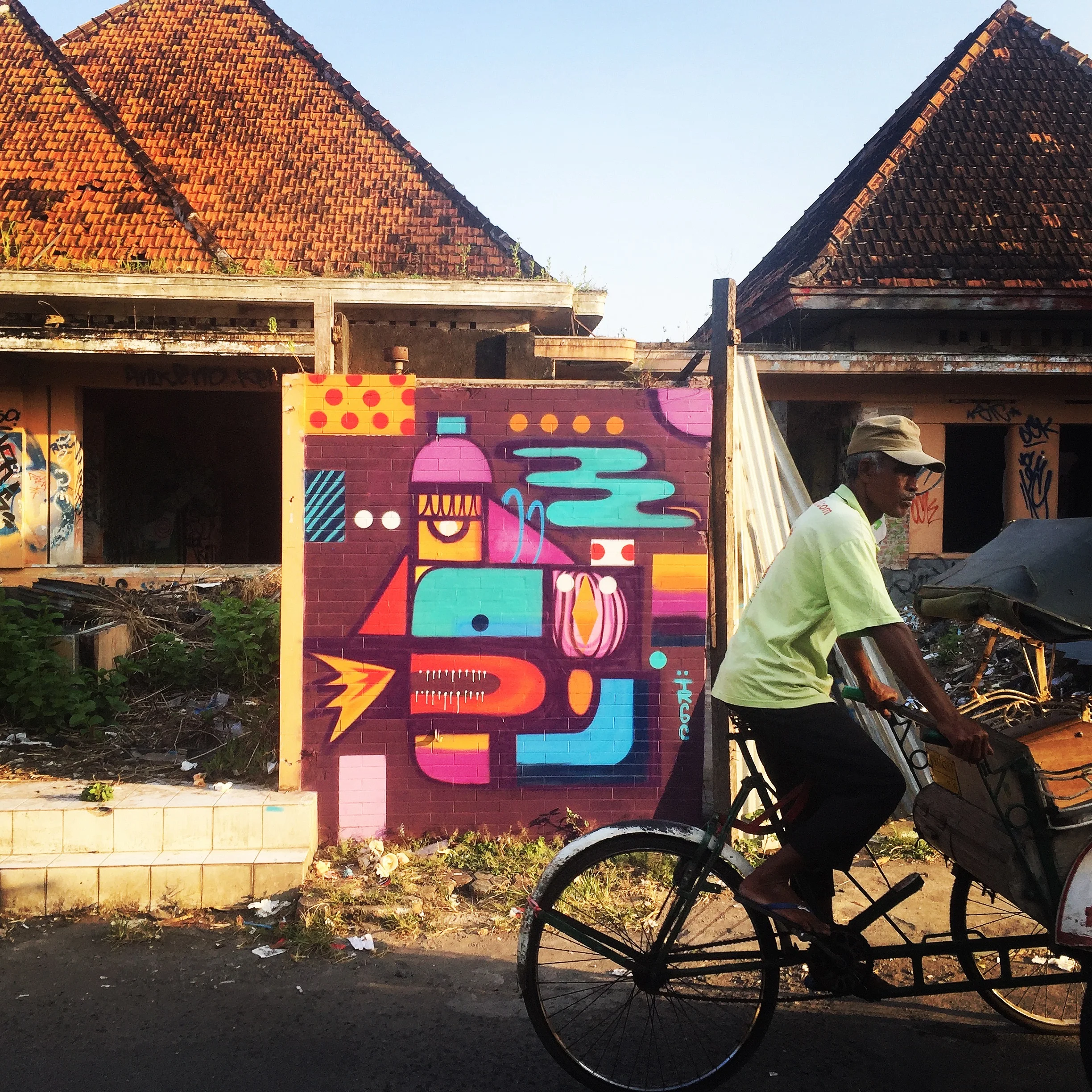 A pedicab passes an abandoned building damaged by the 2006 earthquake, adorned with street art