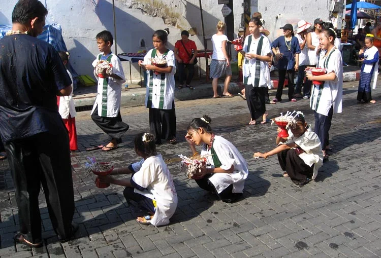 Girls take a break and rest their legs while the procession is held up.