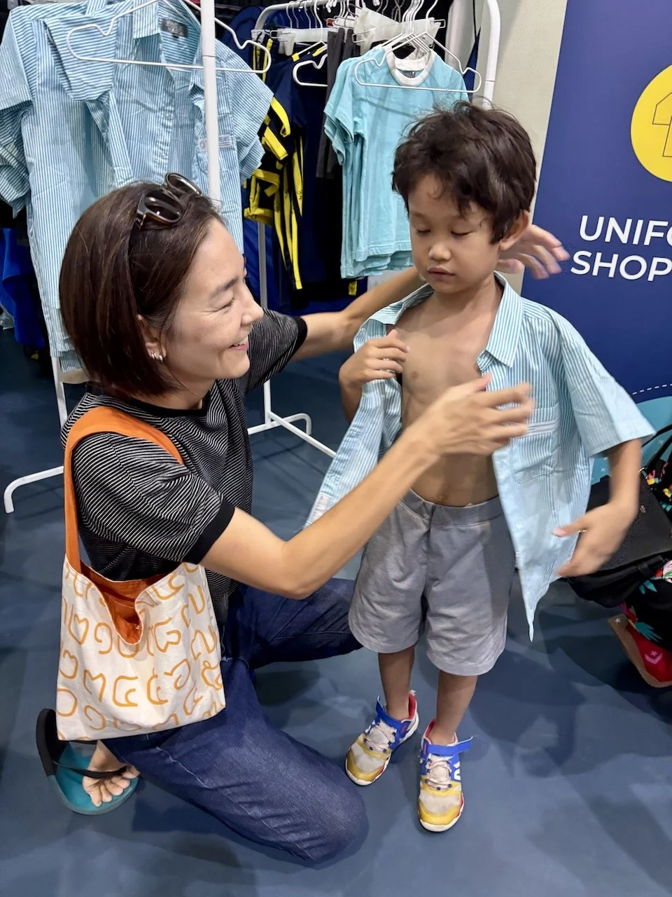 Putting on a test uniform shirt, so he can have his ID photo taken.