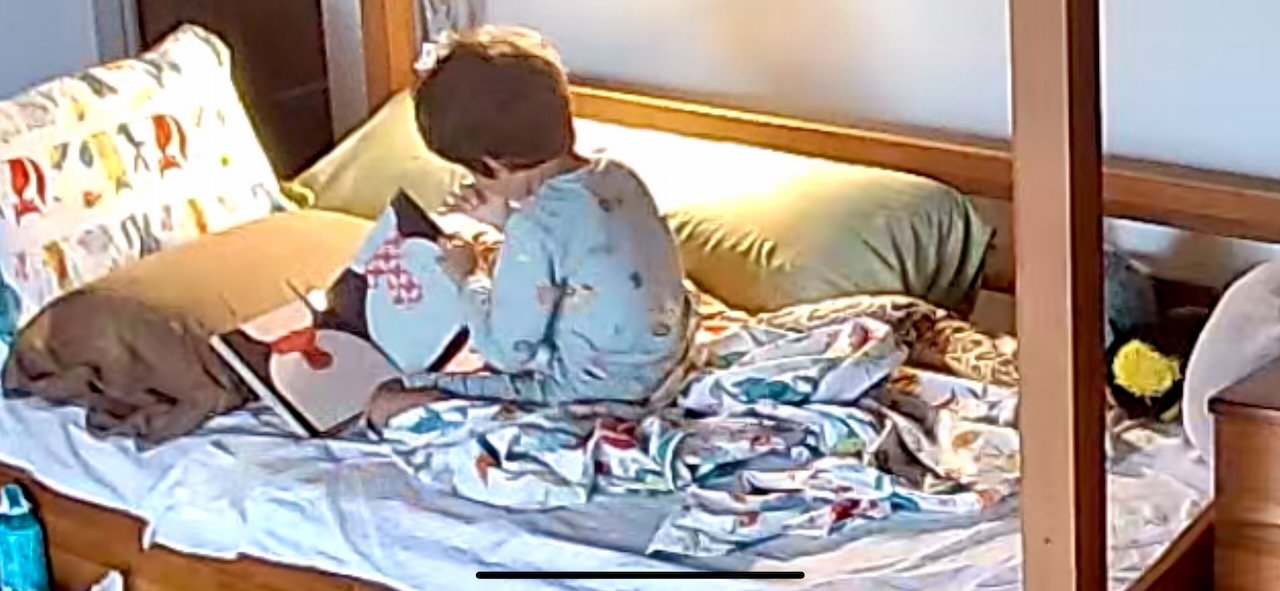 Reading to himself before it's officially time to wake up.