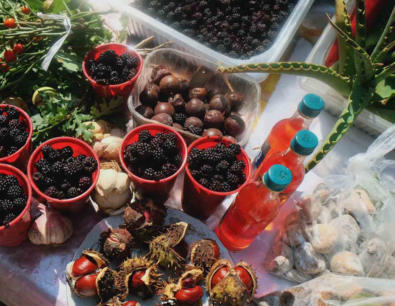 Cups, bottles, tiny blackberries, peppers, and garlic at Green Market in Split.