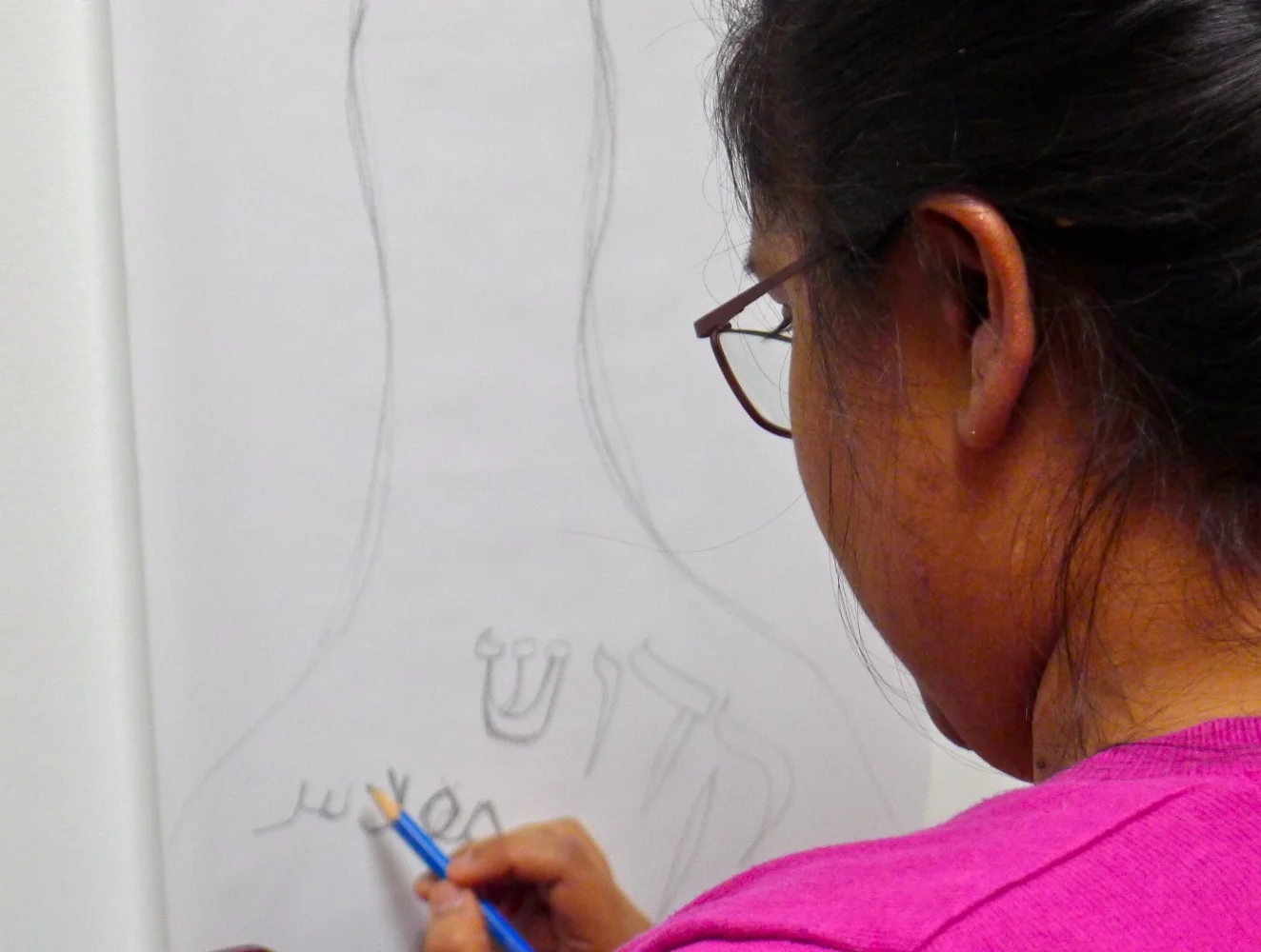 Transcribing the word 'holy' in Arabic and Hebrew onto one of the paper scrolls that will make up the installation.