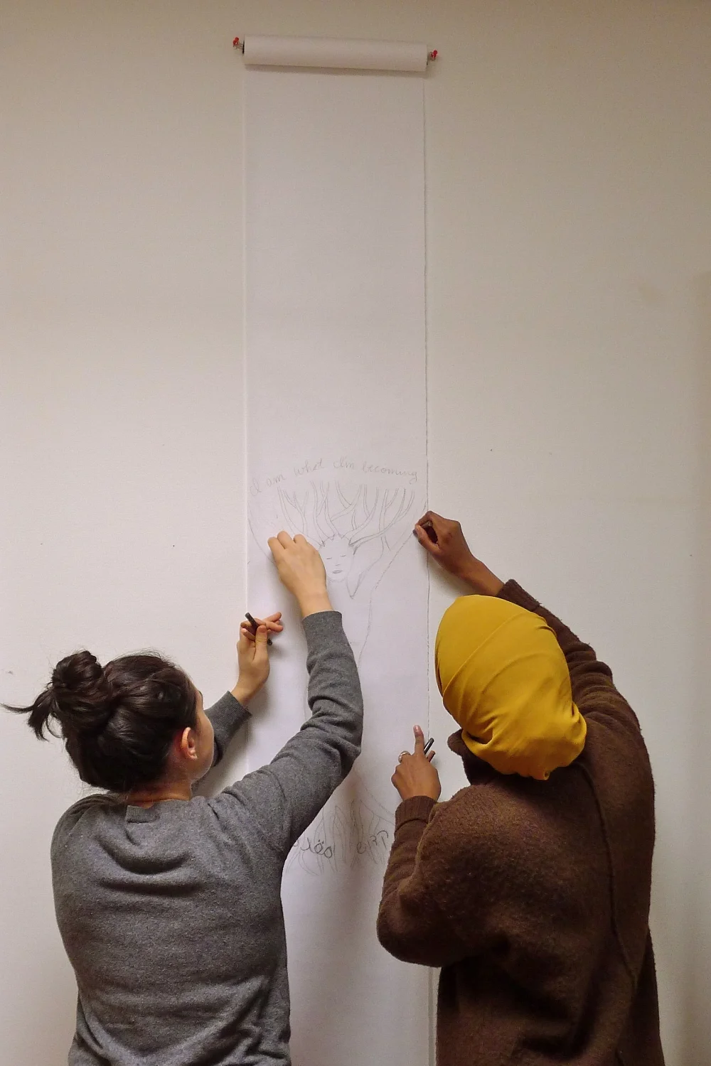 Asma Ali and Tiferet Nashman collaborating on a scroll.