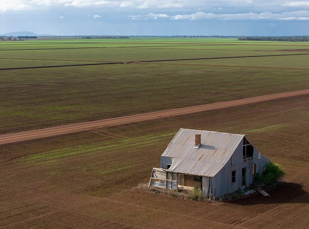 Drone photography shot in rural Queensland with green pastures in the background and an old structure in the foreground.