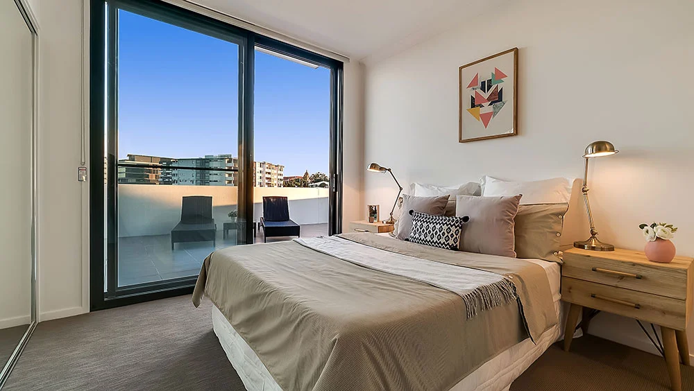 Internal real estate photography of Brisbane apartment bedroom with glass doors onto a private patio — excellent professional marketing.