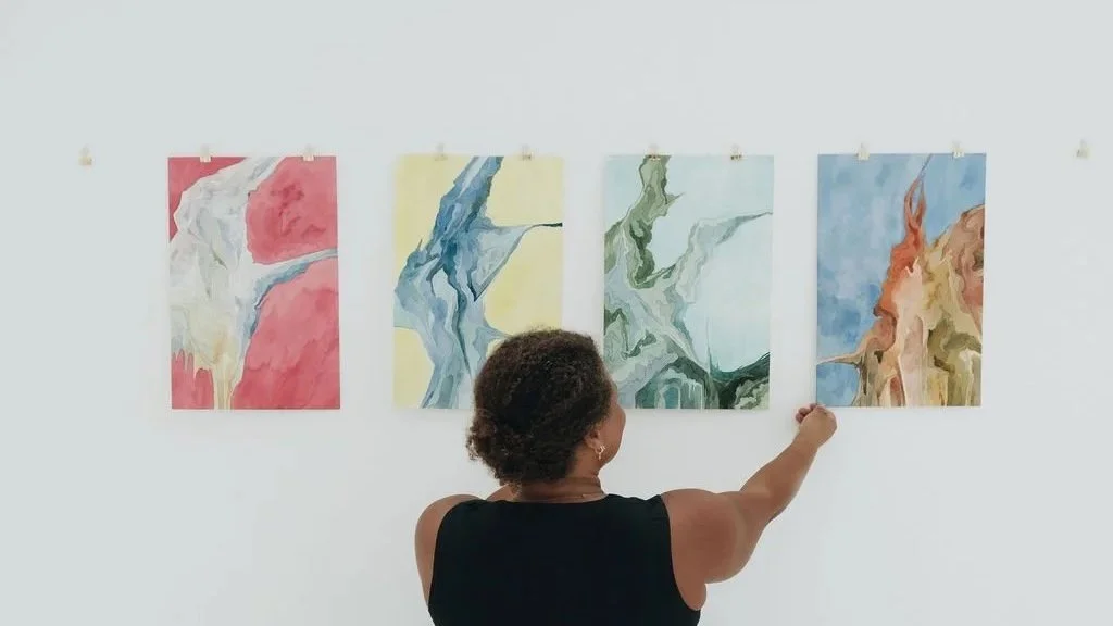 A woman pointing at an abstract painting in an art gallery with four colorful abstract artworks displayed on the wall.