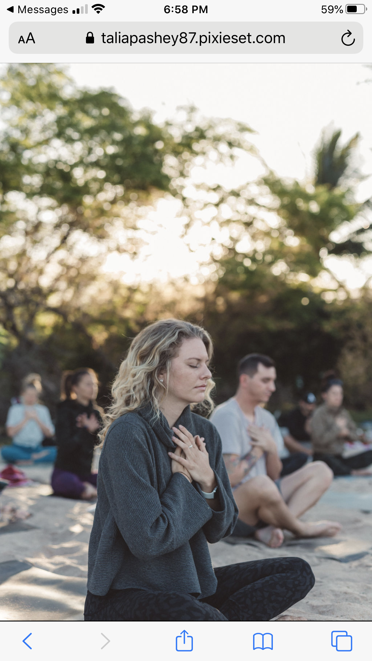 People practicing yoga outdoors during sunset, sitting cross-legged with hands on their chest or heart, in a peaceful meditation.