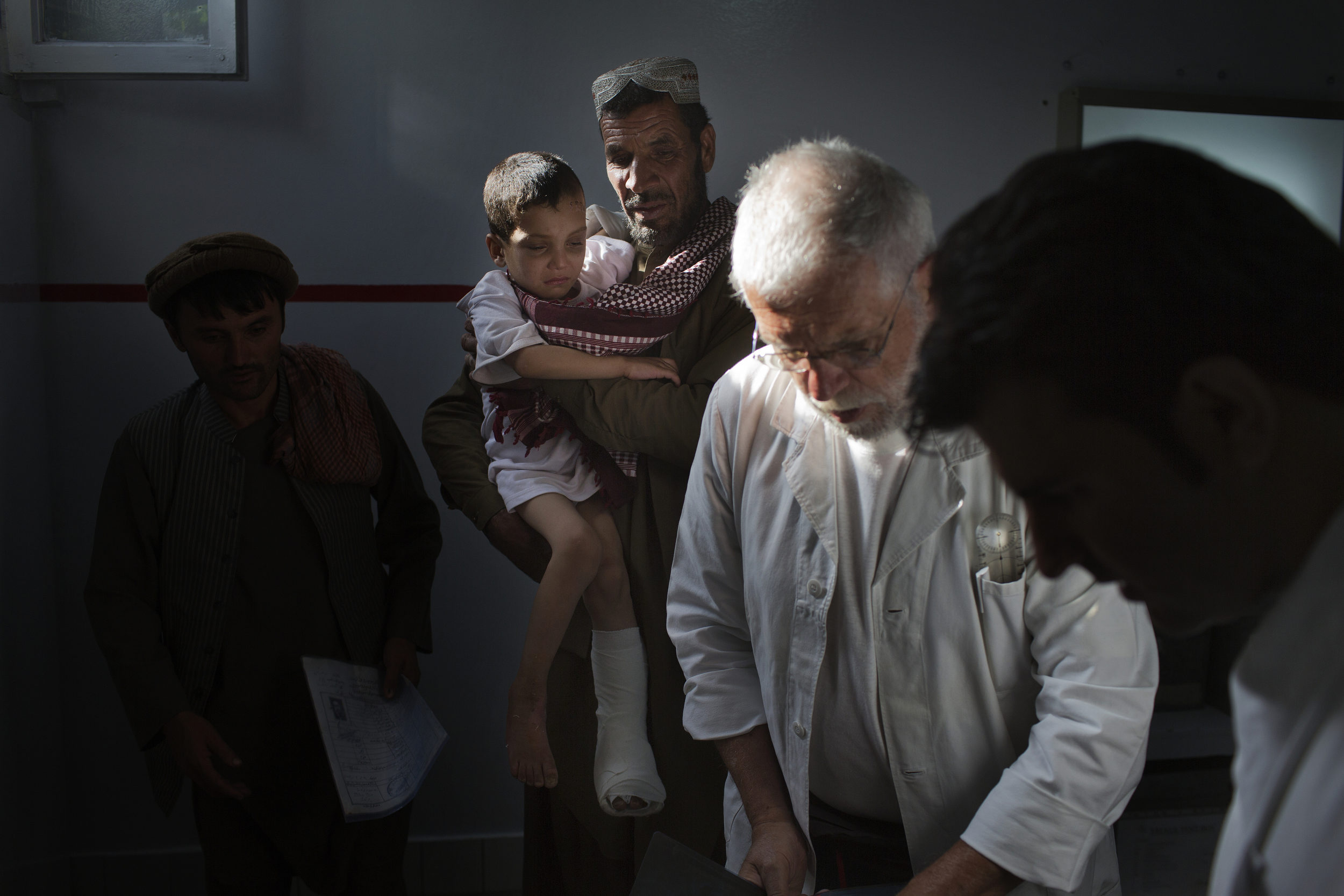  Yasef Naem, 6, is held by his father after an exam by Dr. Alberto Landini. 