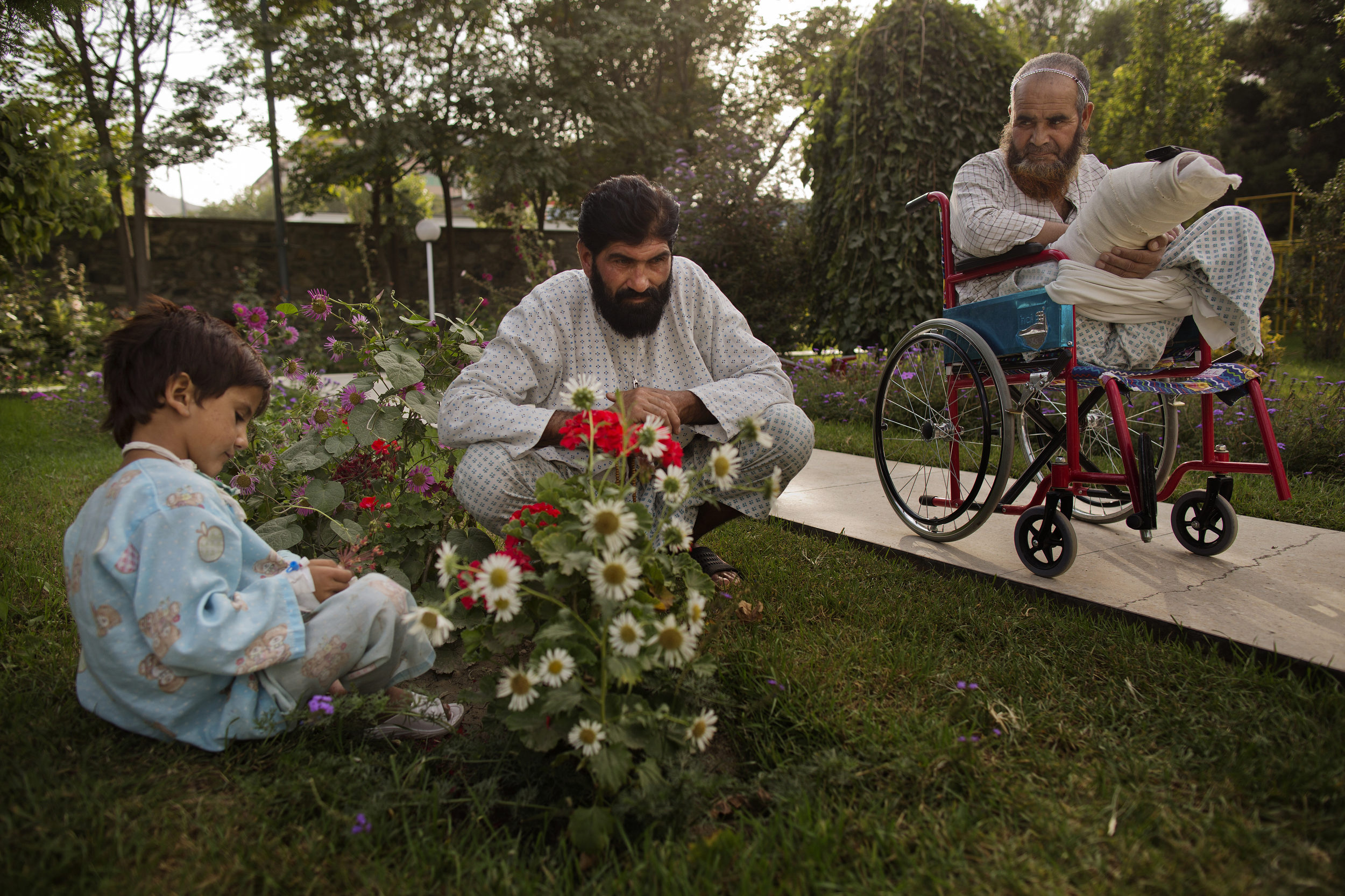  Noor Pacha sits in the garden with his injured son Noorullah, 7, and fellow patient Ab Ahad. 