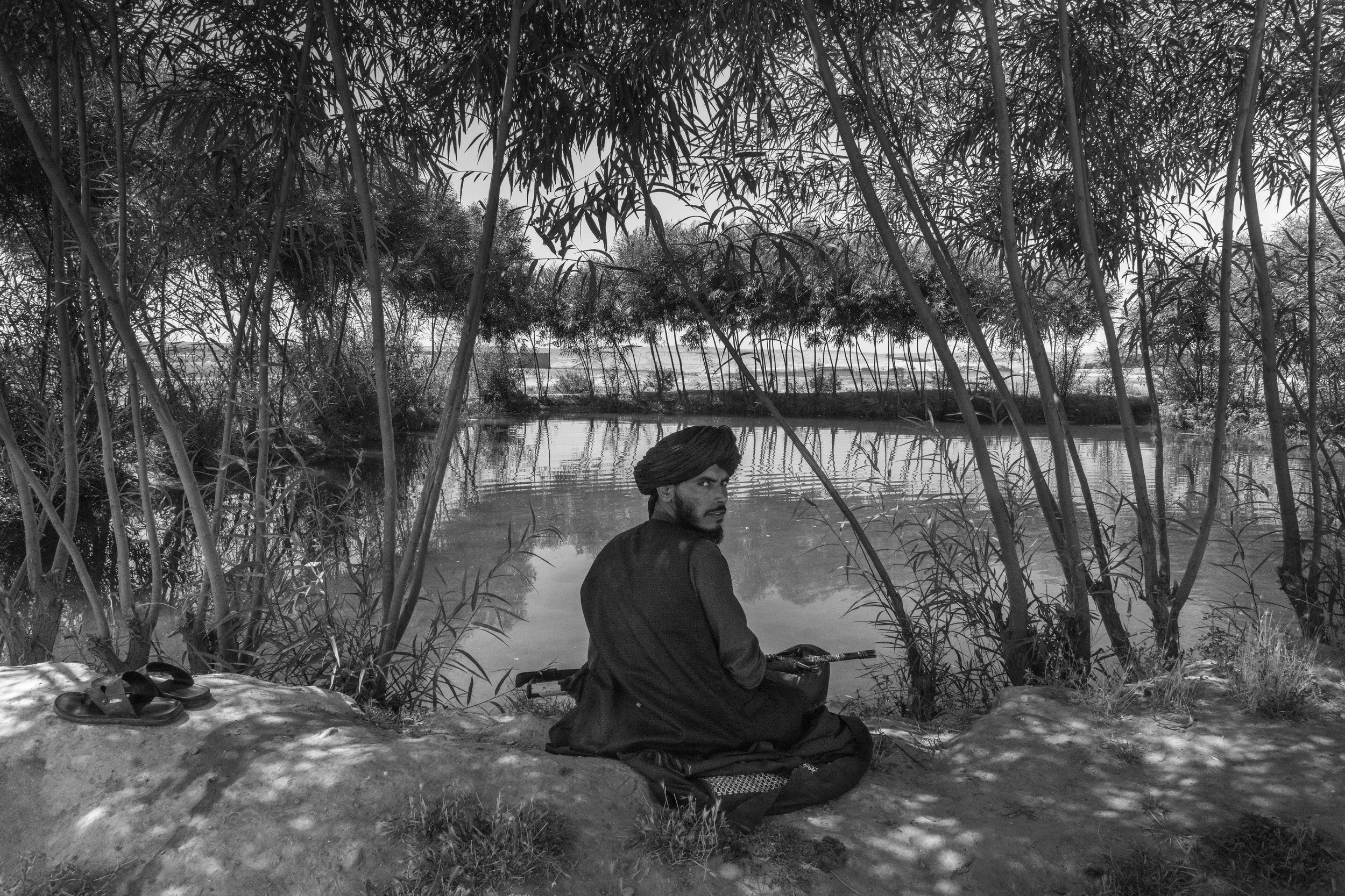 Taliban fighter Hamkar rests by a pond, Helmand.  