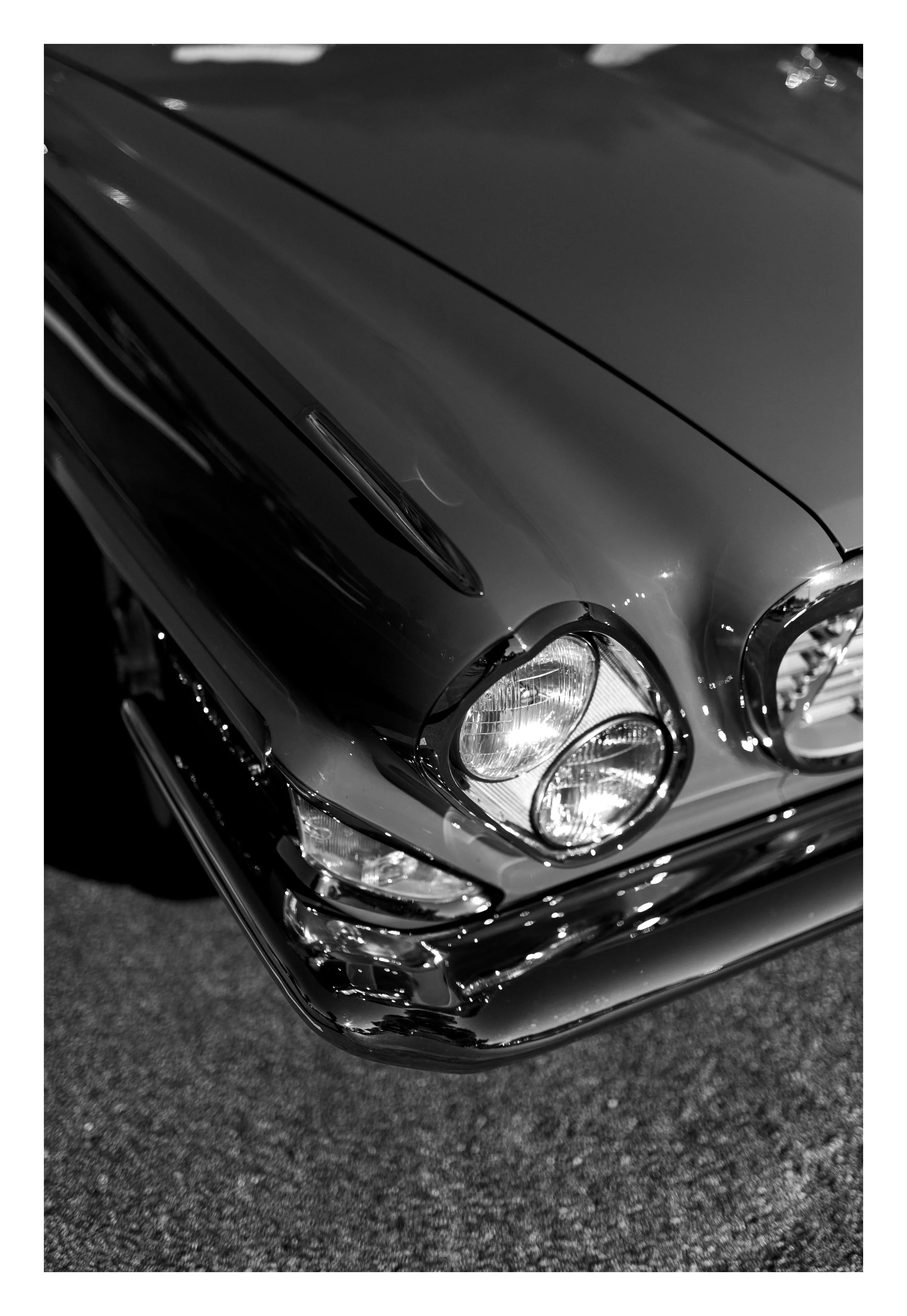 Black luxury car with chrome accents and clear headlights, parked on a dark asphalt surface.