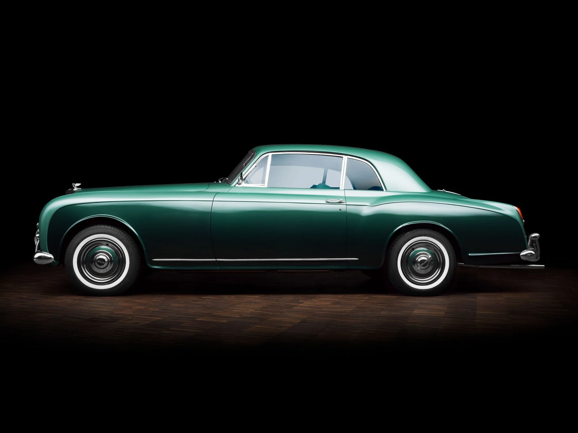 Side profile of a classic green car against black