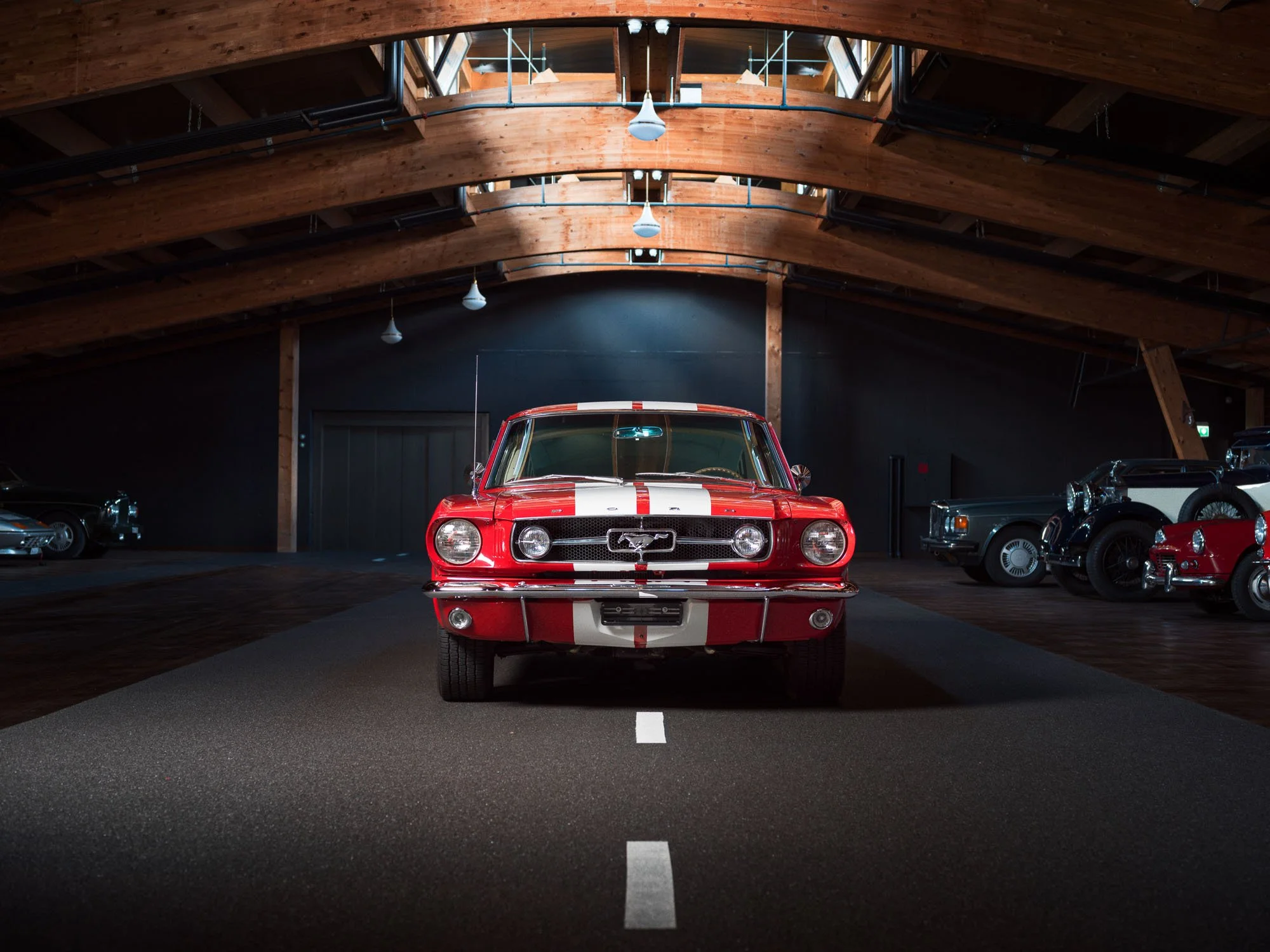 Front view of a red Ford Mustang with white racing stripes