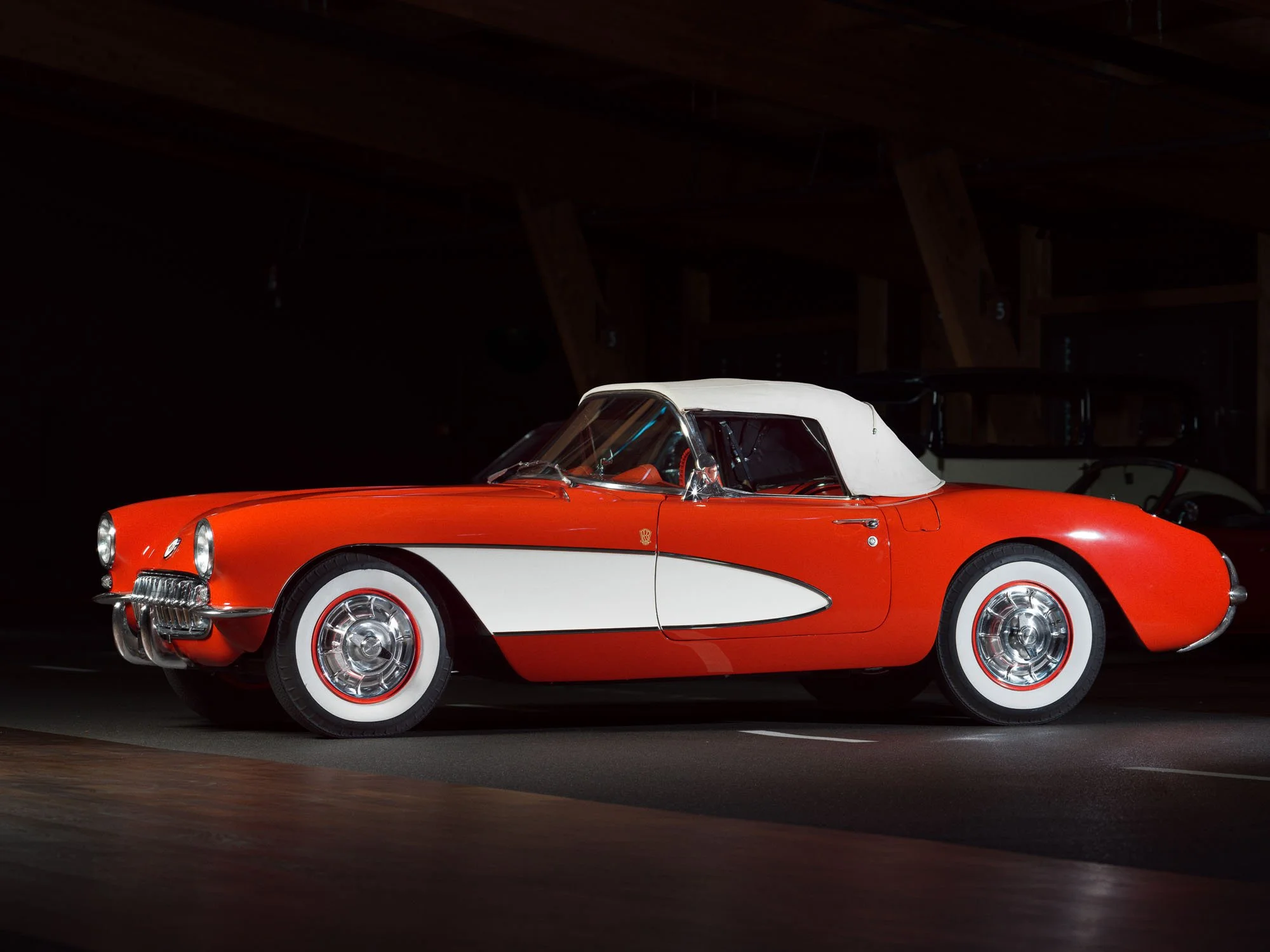 Red and white vintage convertible inside an underground garage