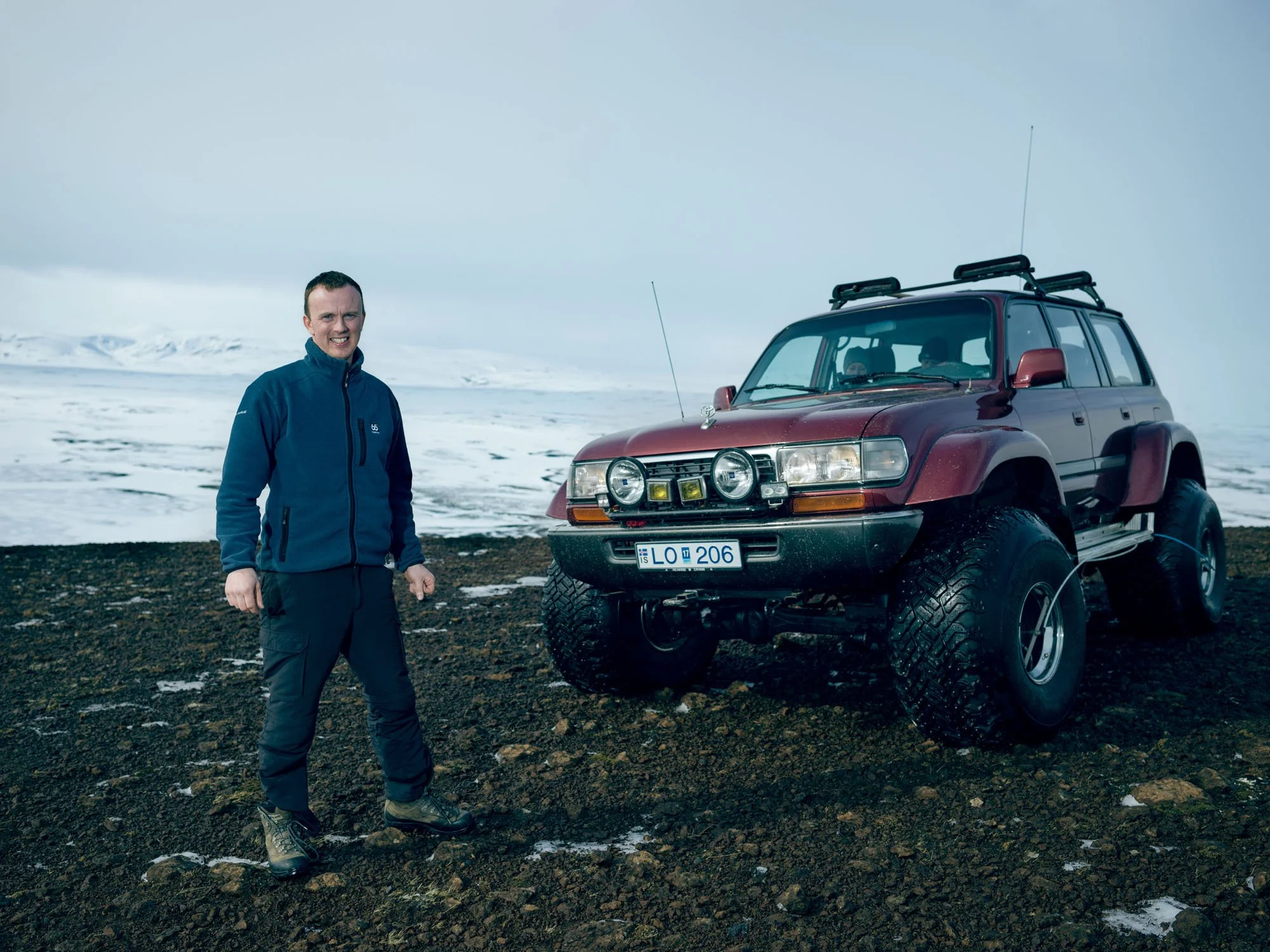 Man standing beside a modified red off-road vehicle