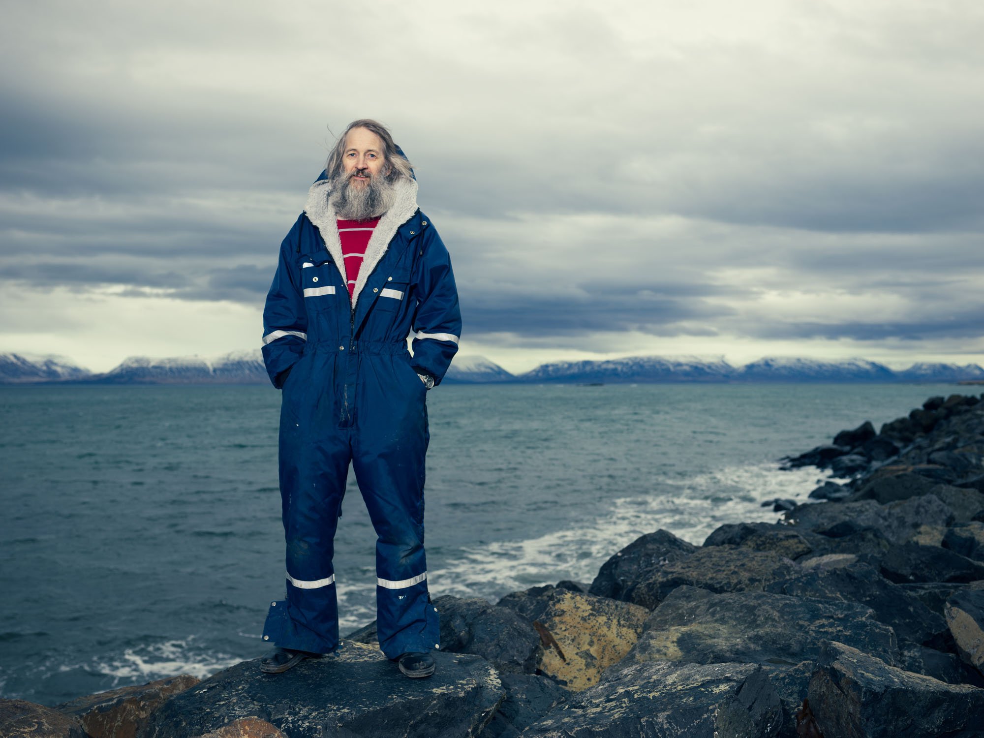 Man in blue winter clothing standing on a rocky coast