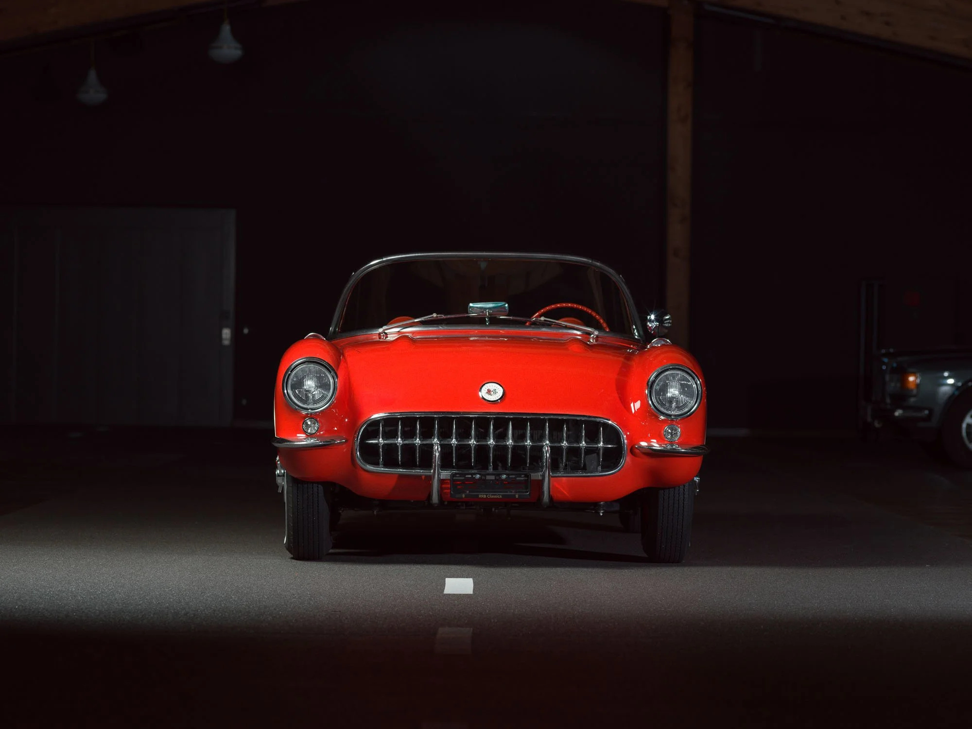 Front view of a red vintage sports car inside a garage