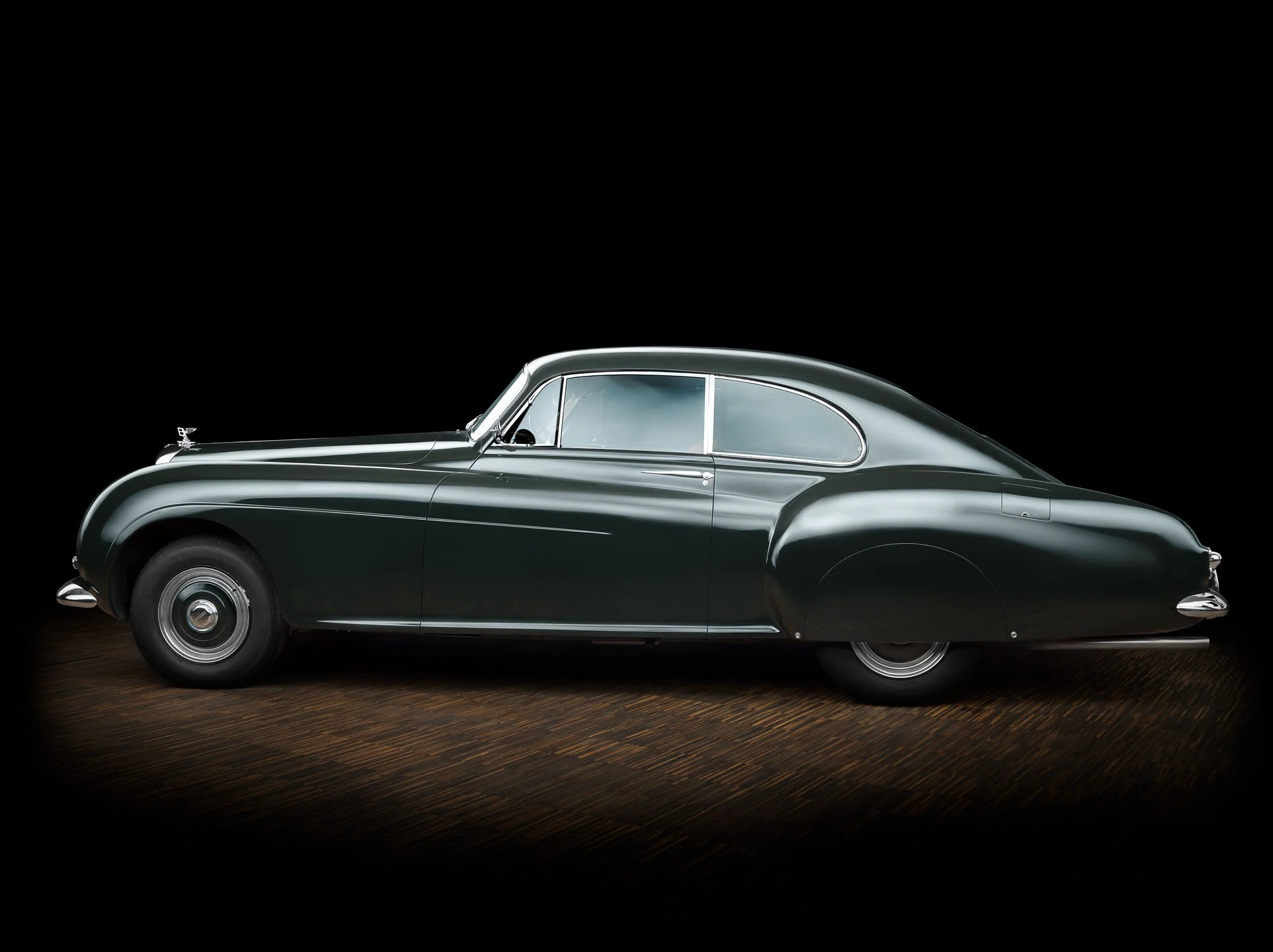 Classic dark coupe photographed against a black background