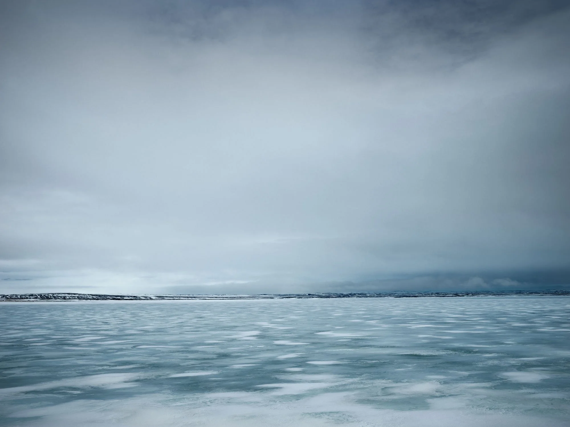 Icy shoreline beneath a low overcast sky