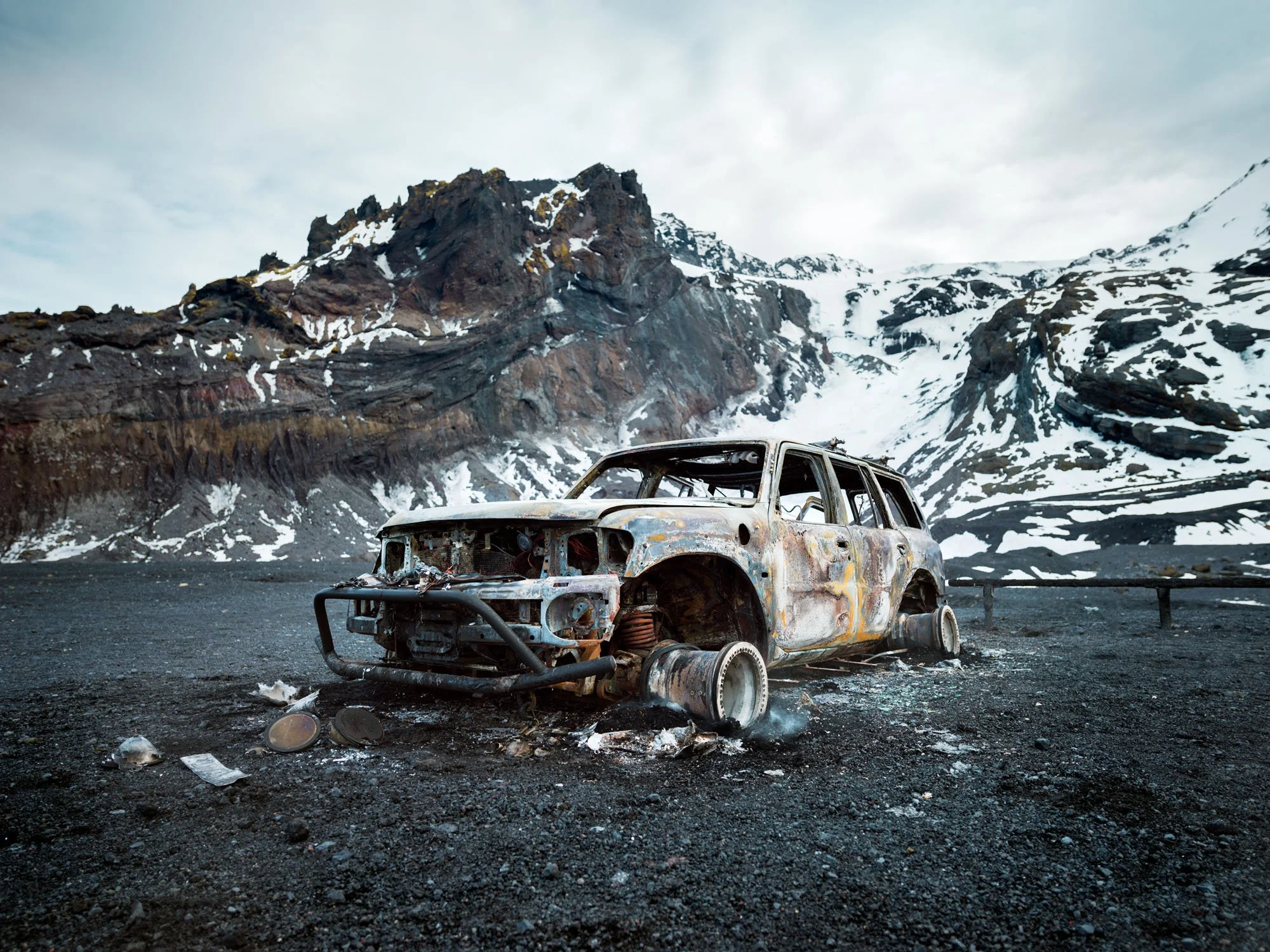 Burnt-out car in a snowy mountain landscape