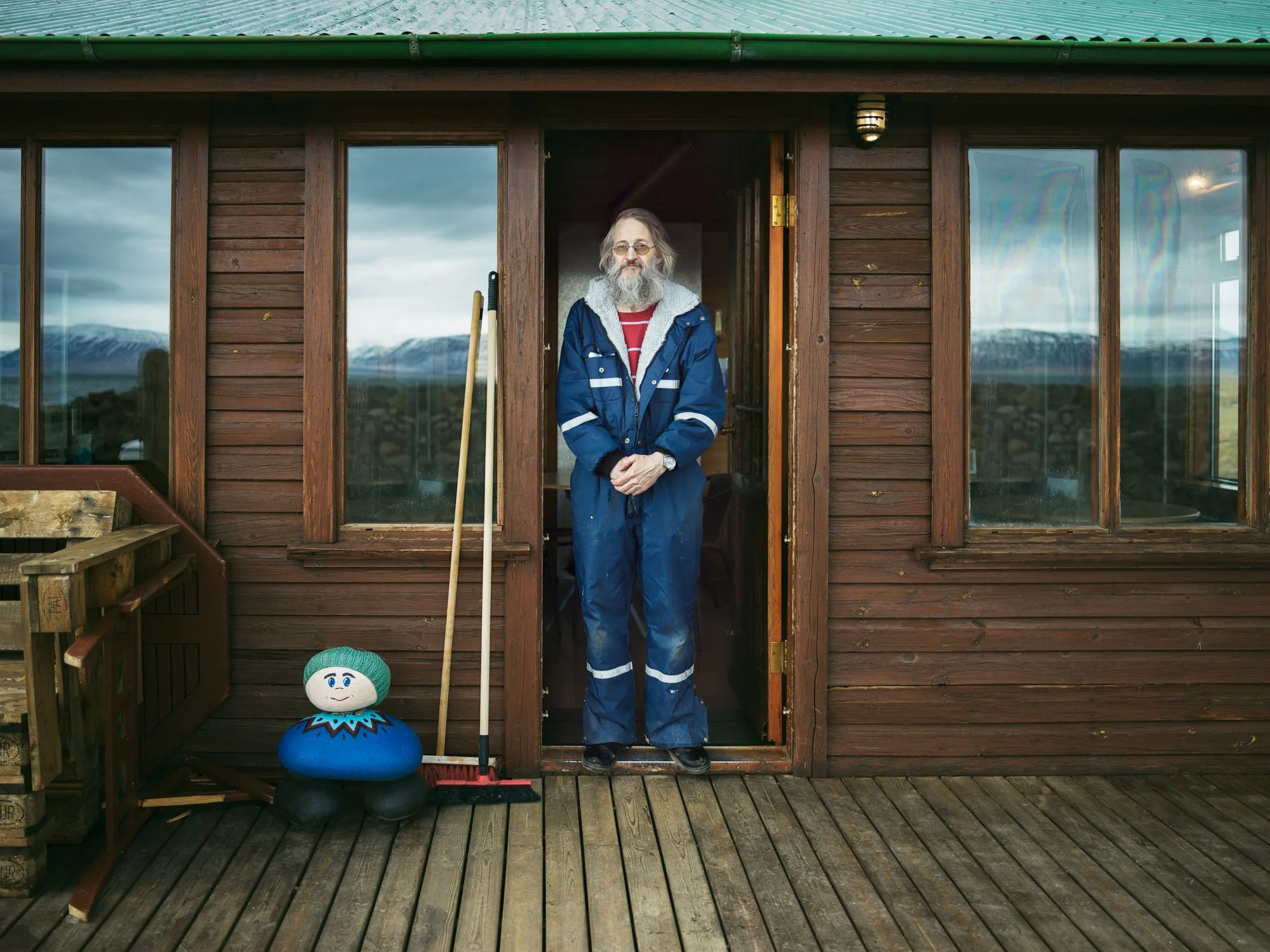 Man in a blue raincoat standing in a wooden doorway
